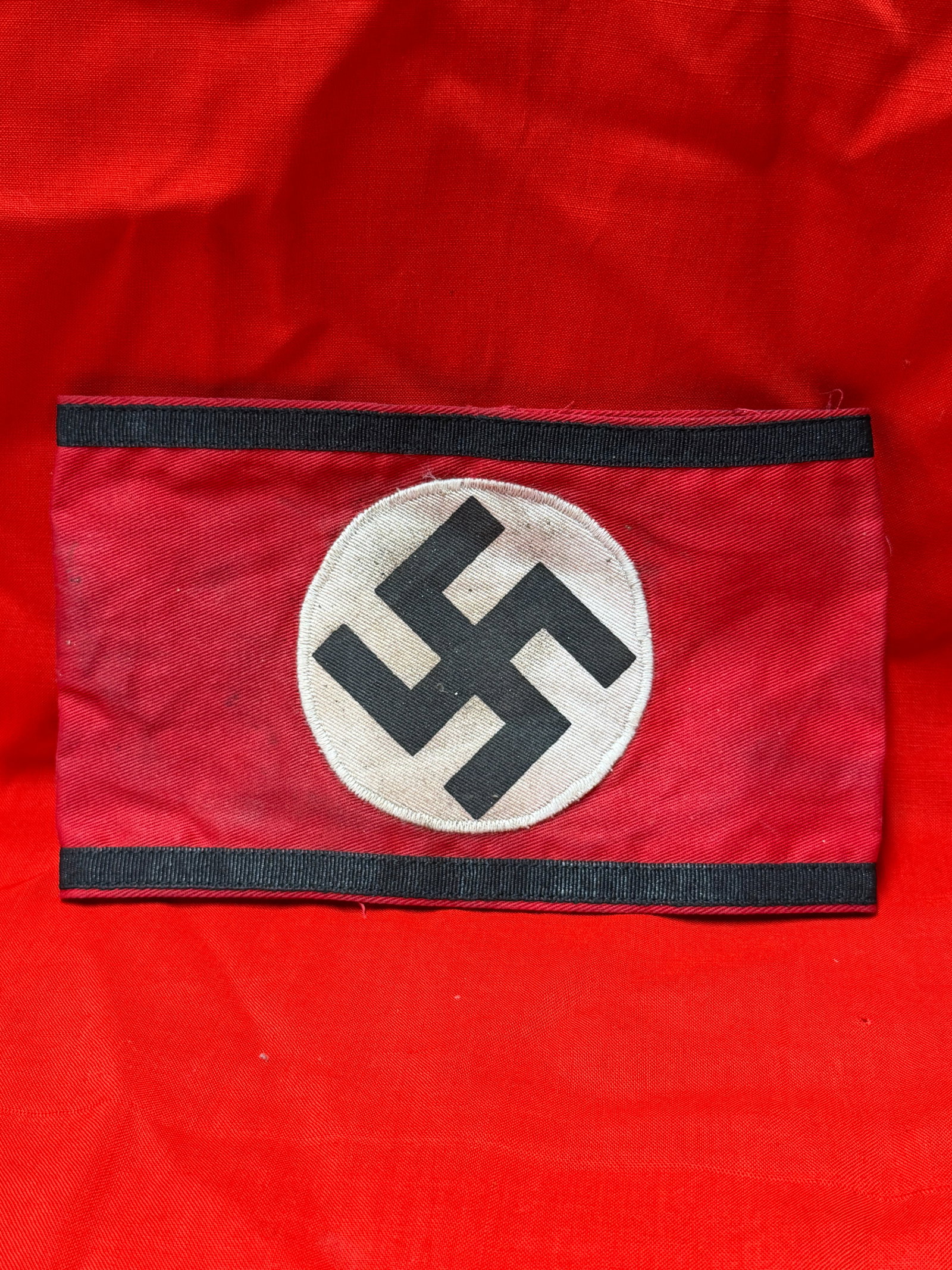 WW2 German Waffen-SS Armband with RZM Paper Tag: WW2 era German Waffen-SS style armband constructed of red fabric with black edge trim and a centrally applied white roundel featuring a black swastika emblem. Interior retains an RZM paper manufacture