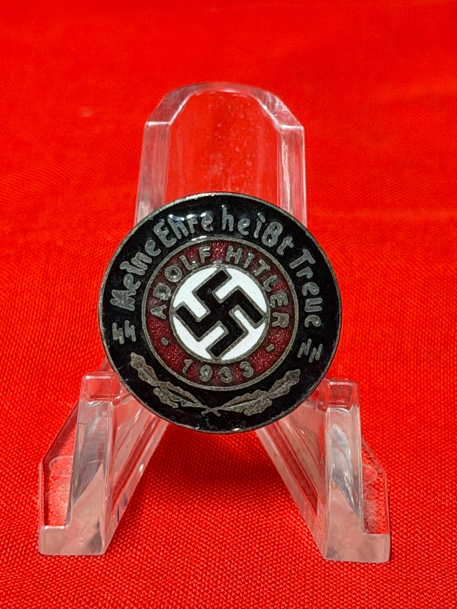 1933 German Tinnie Badge – “Meine Ehre Heißt Treue?? Adolf Hitler Pinback Badge: In our opinion, this is a WWII-era German tinnie-style badge featuring the SS motto “Meine Ehre Heißt Treue” surrounding a central swastika and “Adolf Hitler 1933” inscription. The ba