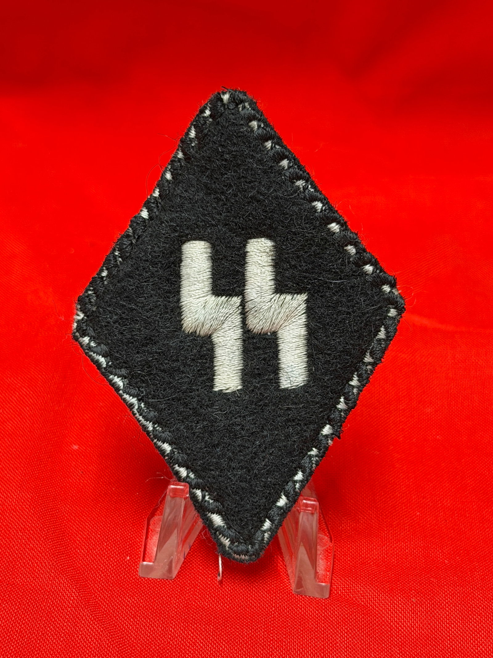 WWII German SS Cloth Insignia Patch With RZM Paper Tag: WWII German SS-style black cloth insignia patch featuring embroidered dual lightning bolt runes on black wool/felt backing with contrasting stitched border. Reverse retains manufacturer-style paper RZ