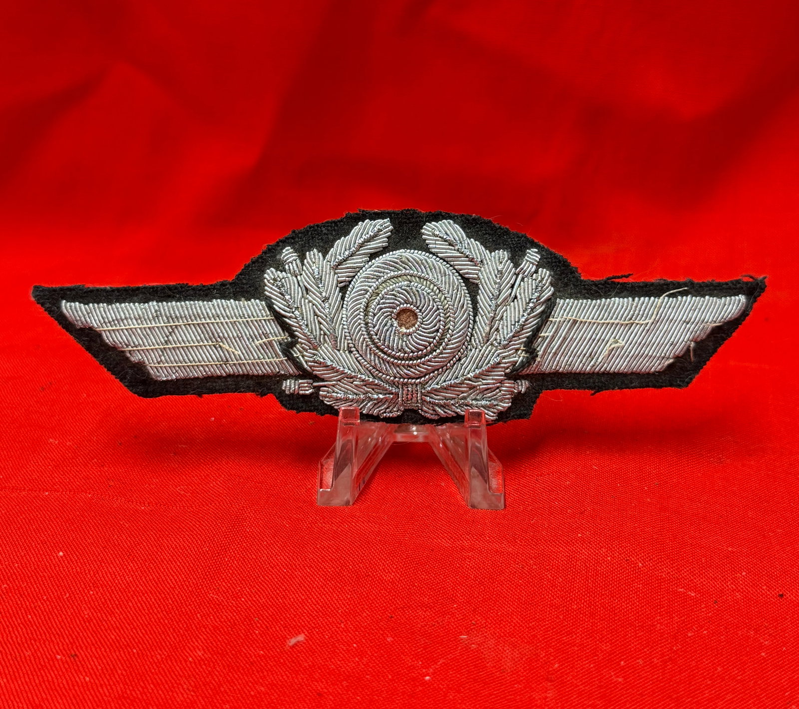 WW2 German Luftwaffe Visor Cap Bullion Cockade with Wreath Insignia Badge: WW2 German Luftwaffe visor cap bullion cockade with wreath insignia badge featuring detailed silver-tone bullion wire embroidery on black cloth backing. In our opinion, this is a striking historical m