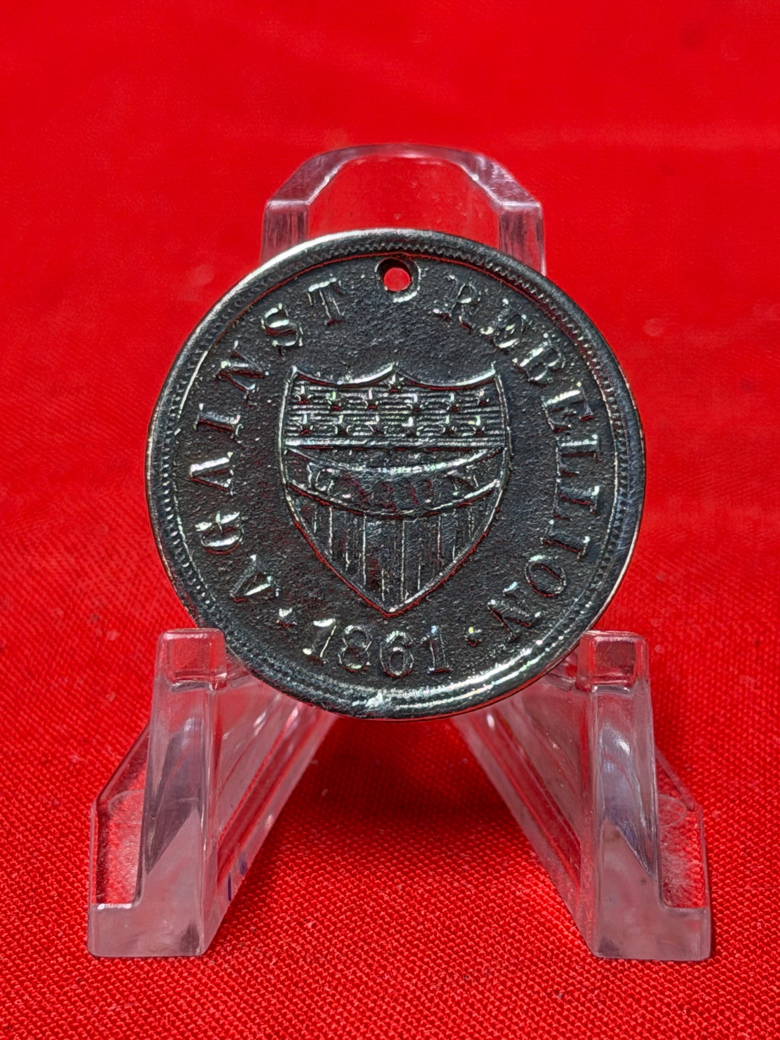 Civil War Era Against Rebellion 1861 Patriotic Token Medallion: Vintage round metal patriotic token featuring the wording “Against Rebellion 1861” surrounding a shield design on the front. Includes a small hole at the top for suspension or display. In our 