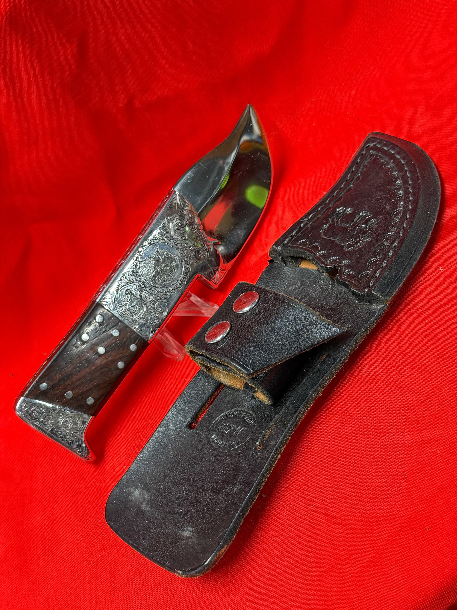 Hand Engraved Buffalo Fixed Blade Hunting Knife With Leather Sheath Signed By Gerald M. Henry: This custom fixed blade hunting knife features detailed hand engraved scrollwork with buffalo artwork on both sides of the blade area and bolsters. The knife has a polished blade, dark wood handle sca