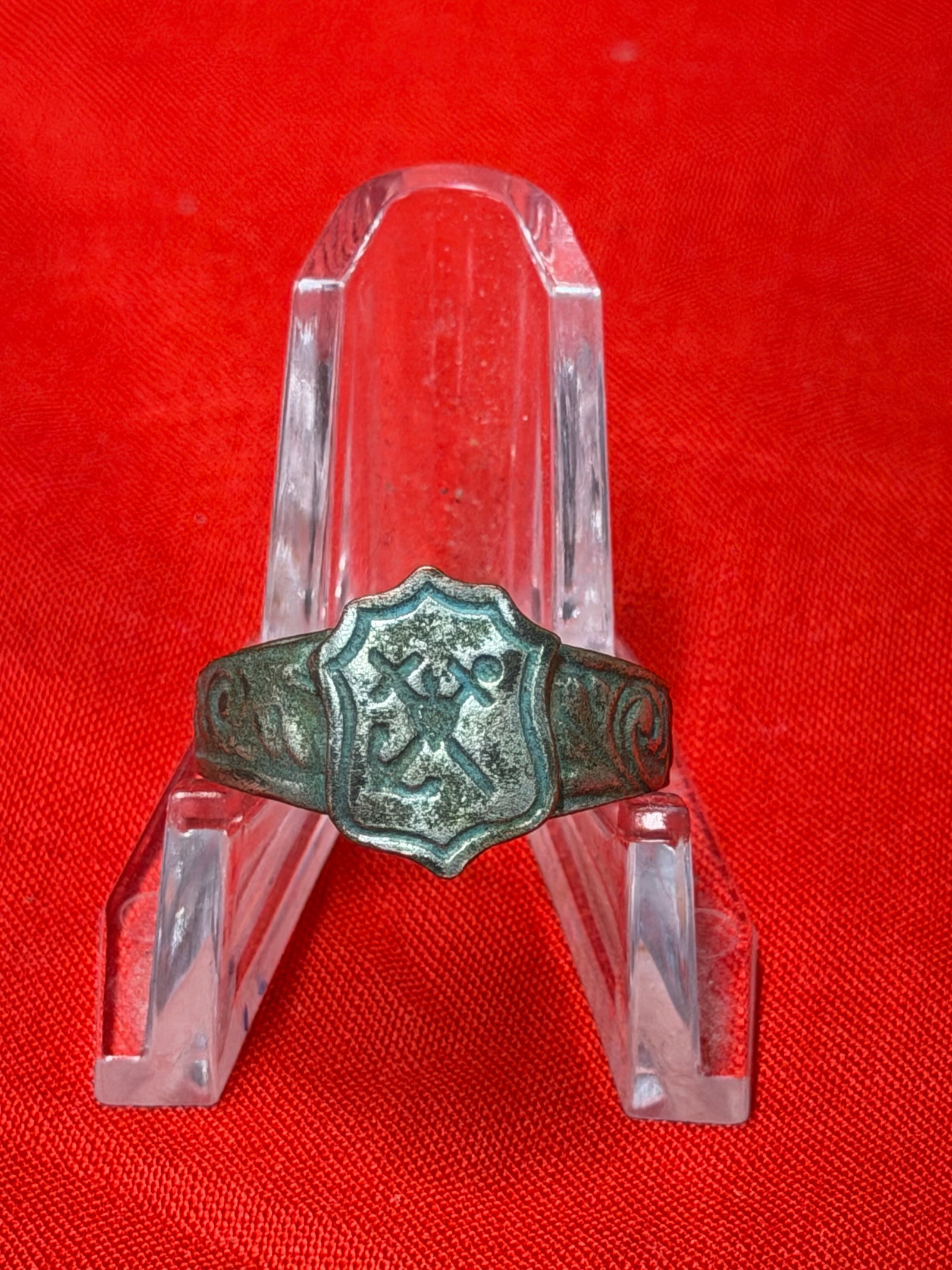 WWII German Kriegsmarine Ring with Heraldic Shield Emblem: WWII German Kriegsmarine-associated ring featuring a heraldic shield centerpiece with crossed nautical-style emblems and decorative engraved shoulders. The ring is made from wartime-era base metal wit