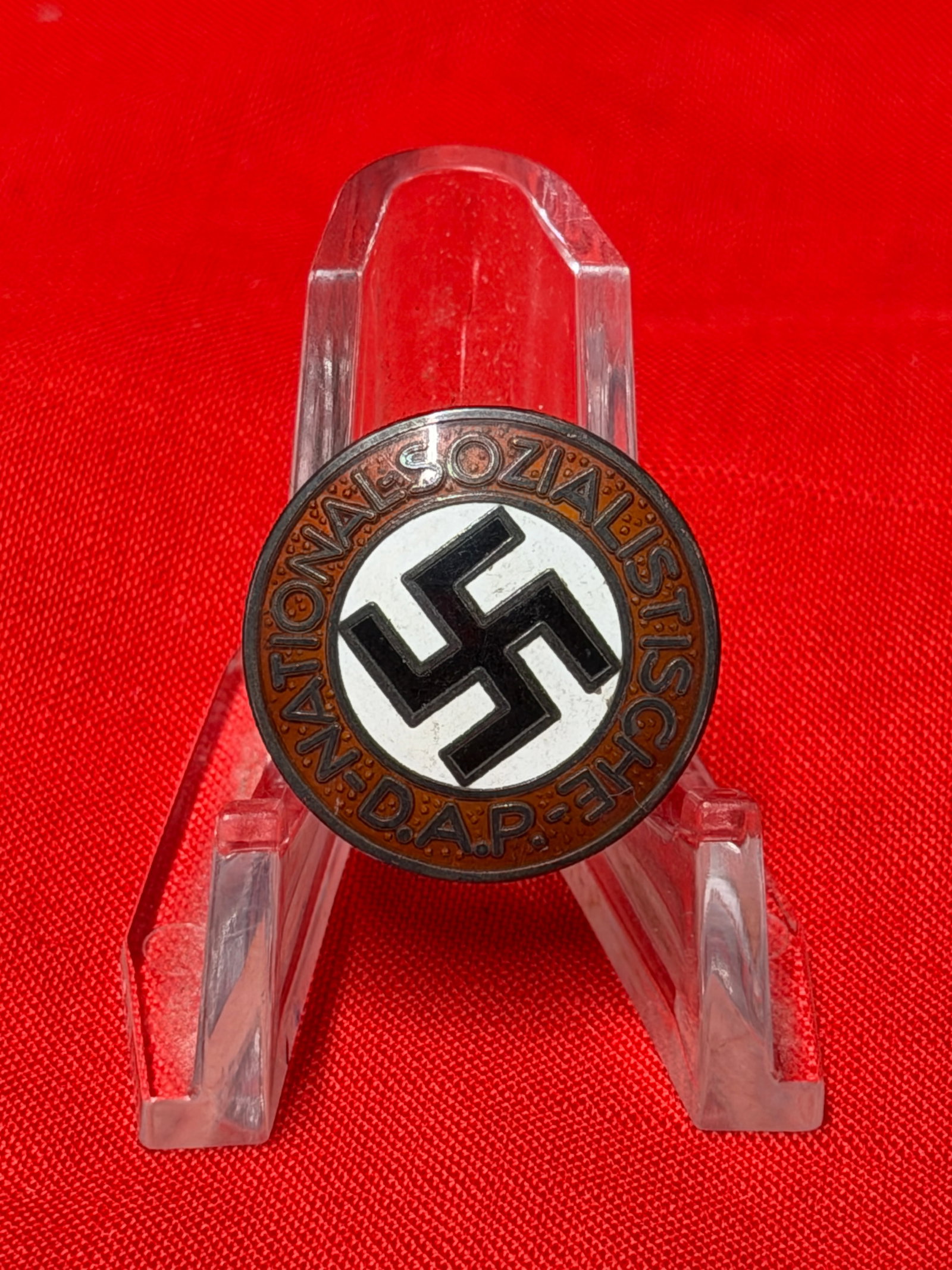 WWII German National Socialist D.A.P. Membership Badge – M1/25 Marked: WWII-era German National Socialist D.A.P. membership badge featuring the black swastika on a white enamel field surrounded by a red enamel border inscribed “NATIONAL-SOZIALISTISCHE D.A.P.” The