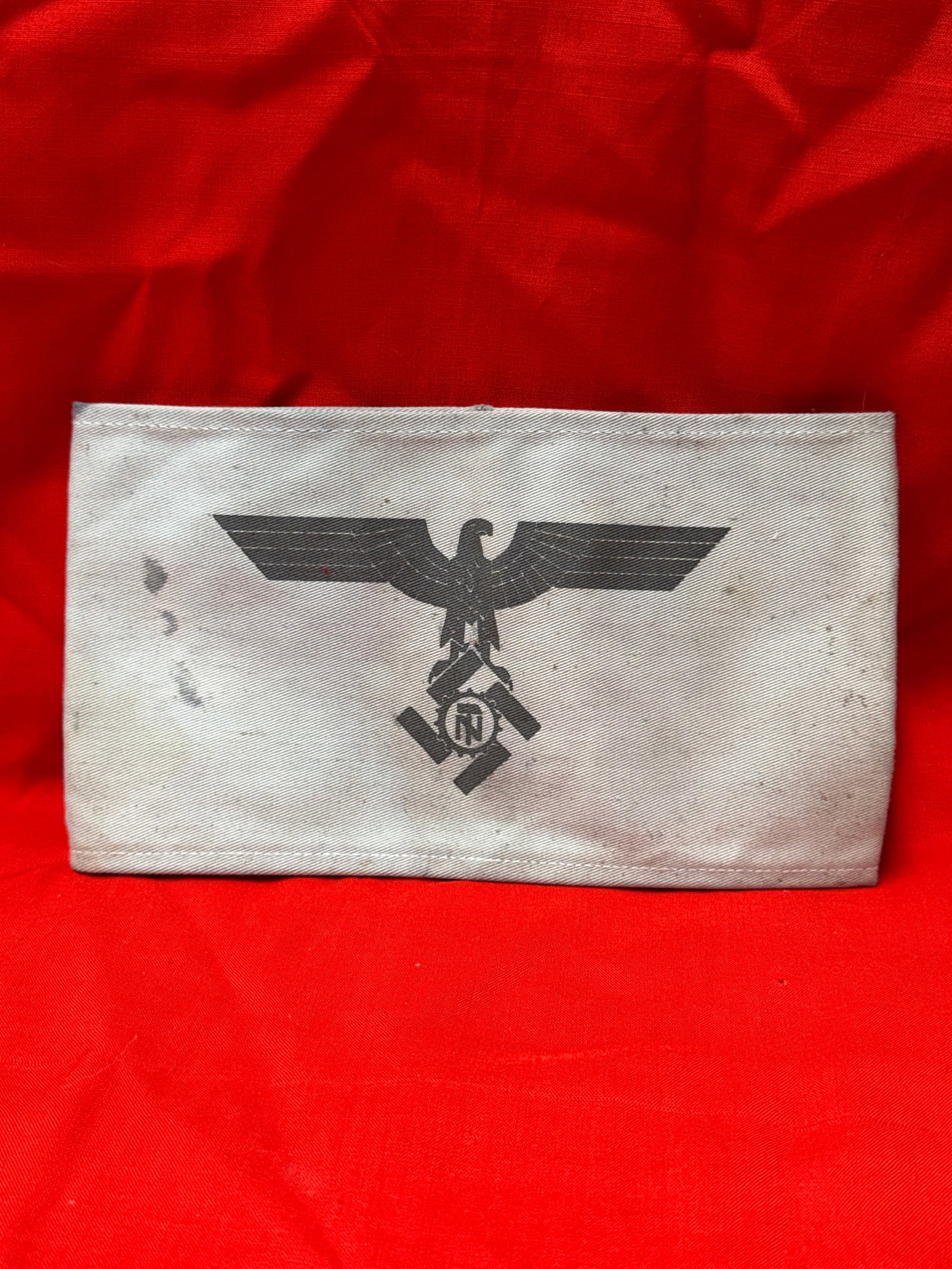 WWII German NSDAP Armband / Sleeve Insignia with RZM Tag – Third Reich Political Uniform Piece: WWII-era German NSDAP-related cloth insignia panel featuring the Third Reich eagle above a swastika emblem. Constructed from light tan/gray cotton twill material with stitched edges and printed black 