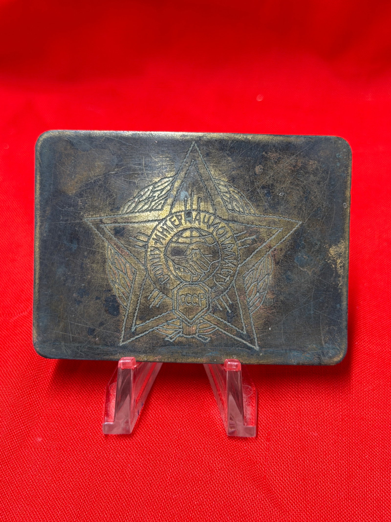 WW2 Soviet USSR Communist International Friendship Belt Buckle: Soviet-era metal belt buckle featuring an engraved five-point star emblem with handshake motif and Cyrillic inscription associated with international friendship and socialist unity themes. The design 