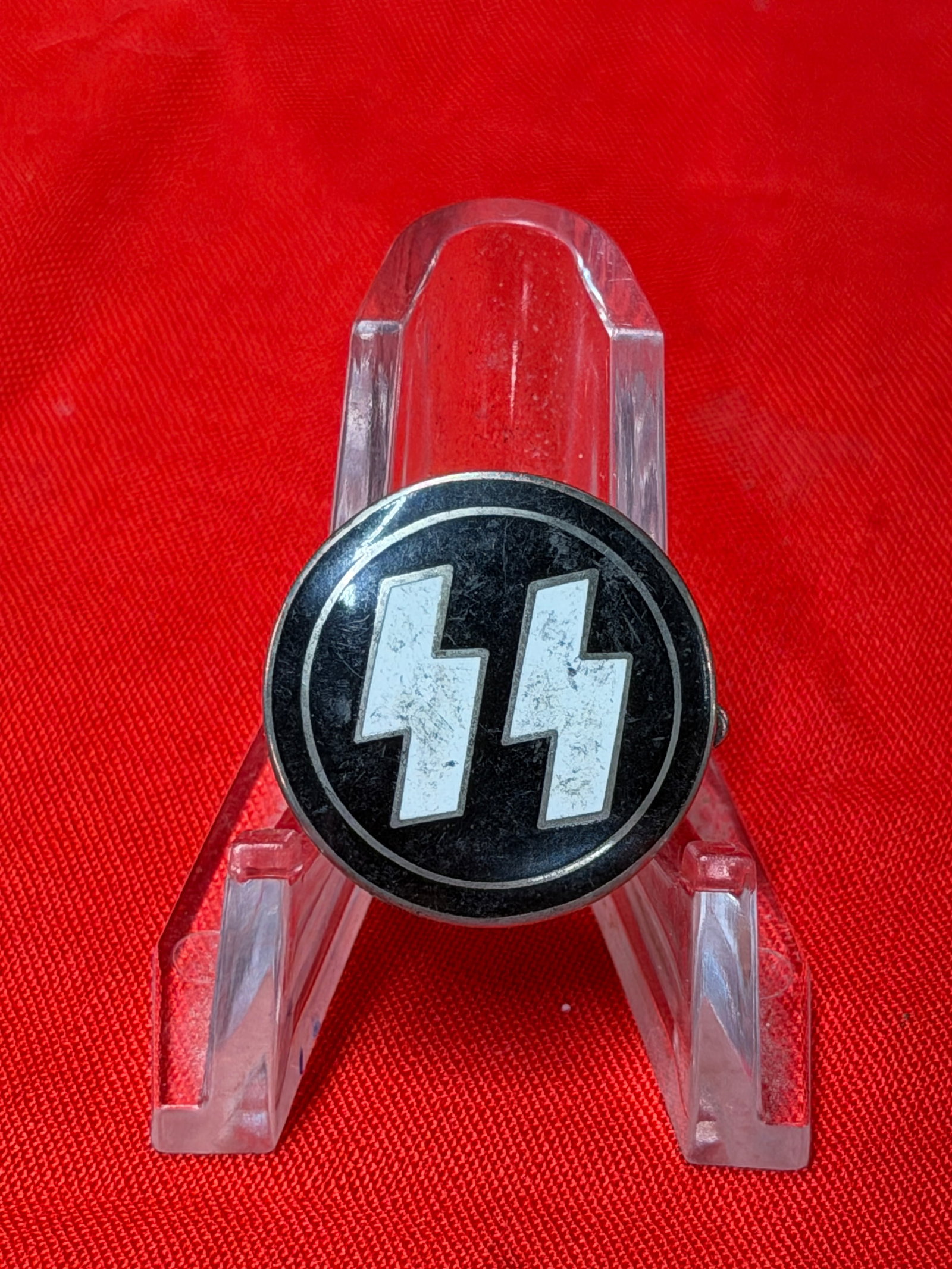 WWII German SS Double Rune Lapel Pin Badge – RZM M1/4 Marked: WWII-era German SS-style lapel pin featuring the iconic double lightning bolt rune emblem in white enamel over a black circular field. The reverse is marked “RZM M1/4 GES. GESCH.” indicating p
