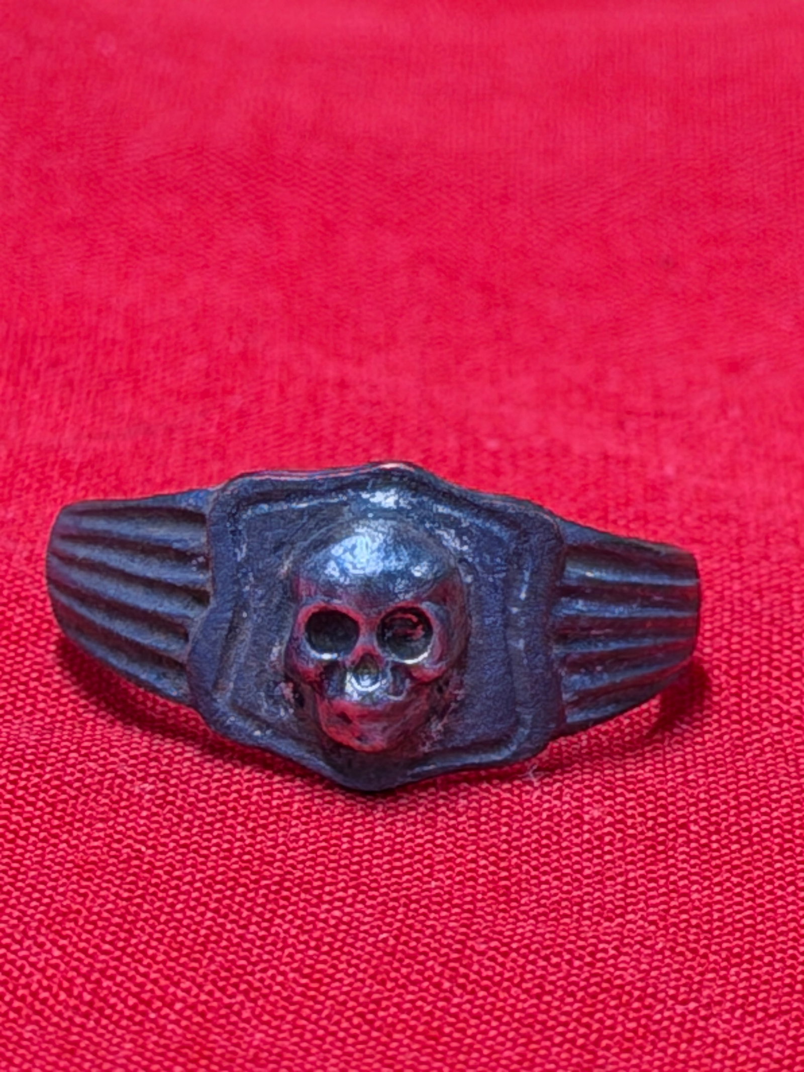 WW2 German Totenkopf SS Officer Style Silver Skull Ring: This silver colored skull ring features the classic Totenkopf style design associated with German SS officer symbolism from the WW2 era. The ring displays a raised skull centerpiece with detailed faci