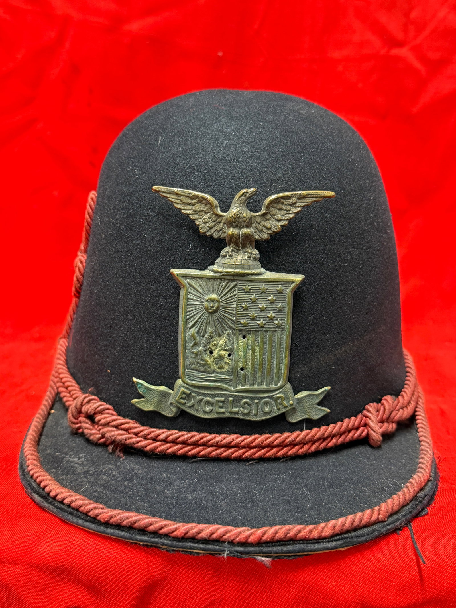 New York State Militia Style Civil War Era Shako Hat with Excelsior Eagle Badge: Antique Civil War era style New York militia shako hat featuring a large “Excelsior” New York state eagle and shield badge on the front with red cord trim decoration. This style of headgear is