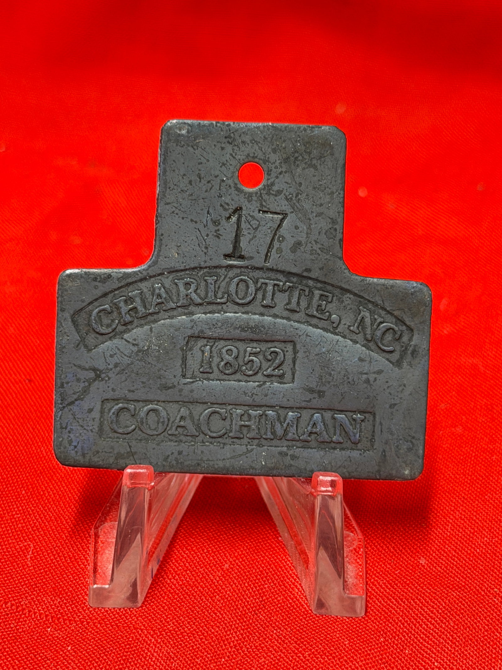 Antique 1852 Charlotte NC Coachman Slave Tag Number 17 Relic: Antique metal slave tag marked “17 Charlotte, NC 1852 Coachman.” Features embossed lettering with original number designation and occupation marking on front along with mounting hole at top. I