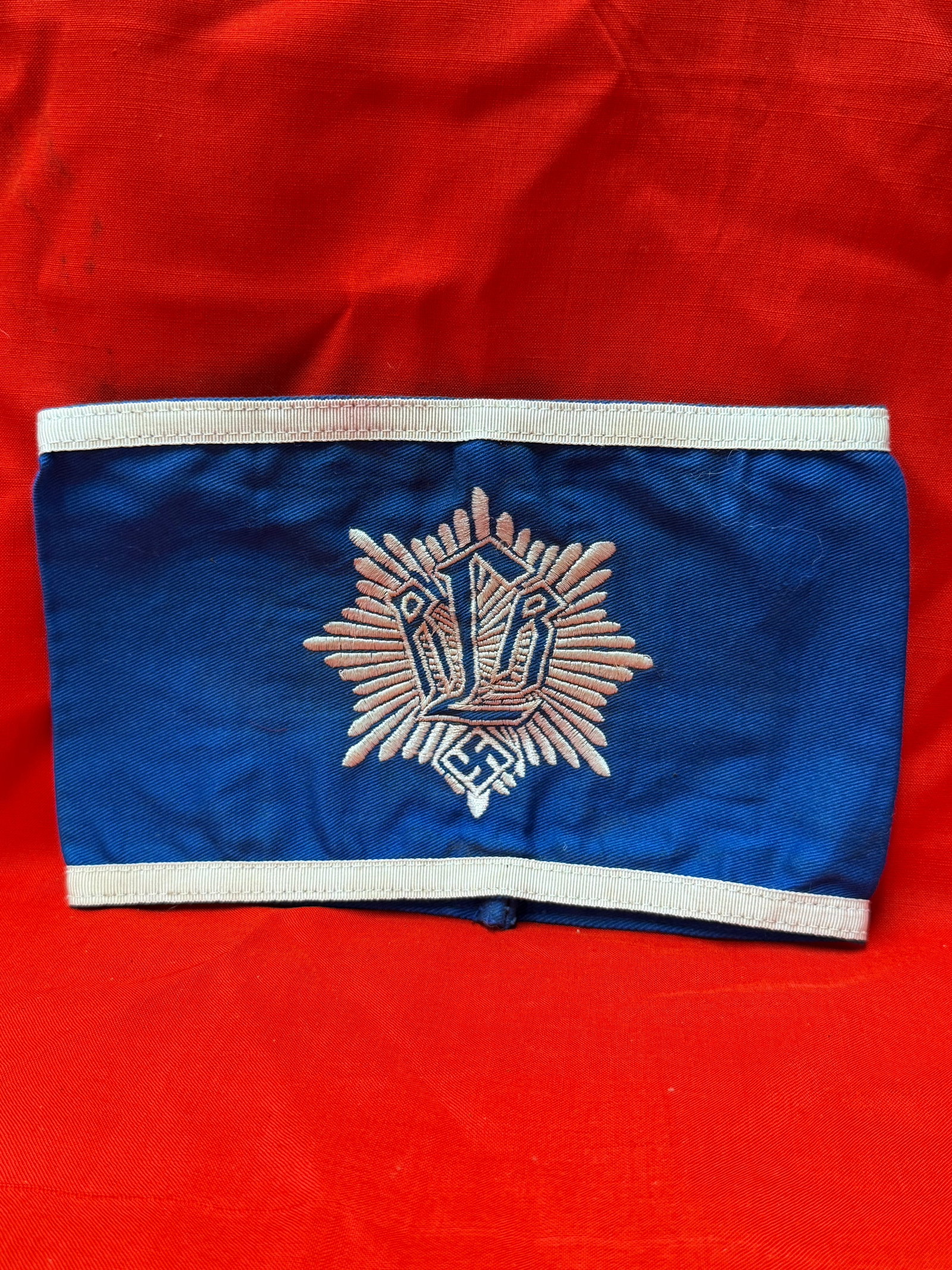 WW2 German DRL Sports Organization Blue Armband Embroidered Insignia: WW2 German blue cloth armband featuring white trim and embroidered DRL sports organization style insignia with sunburst pattern and swastika emblem design. Constructed from blue fabric material with s