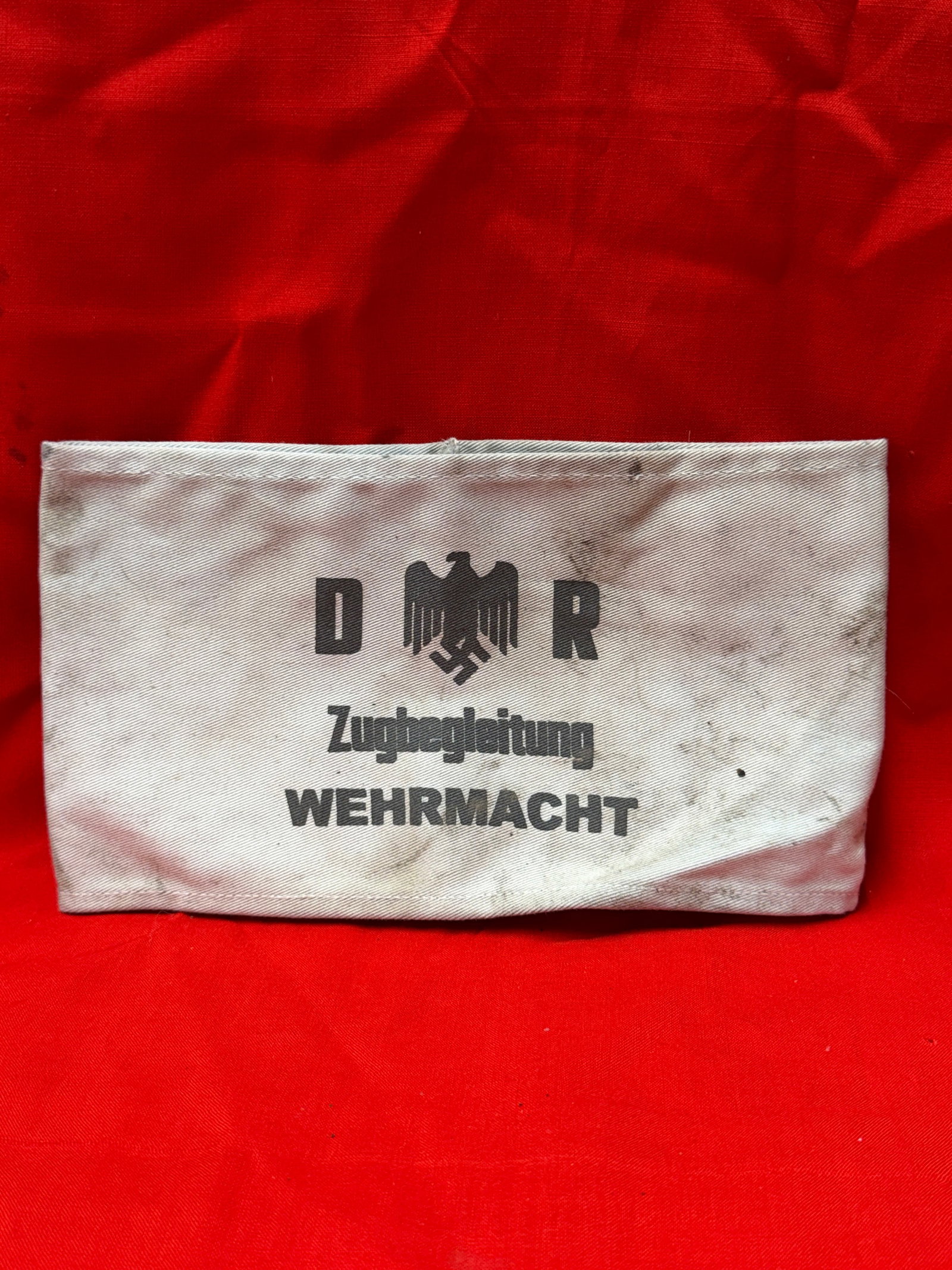 WW2 German DR Wehrmacht Zugbegleitung Cloth Armband Railway Escort Sleeve Band: WW2 German white cloth armband featuring printed DR eagle insignia with “Zugbegleitung Wehrmacht” text design. Constructed from white cotton style fabric with sewn edges and slip through sleev