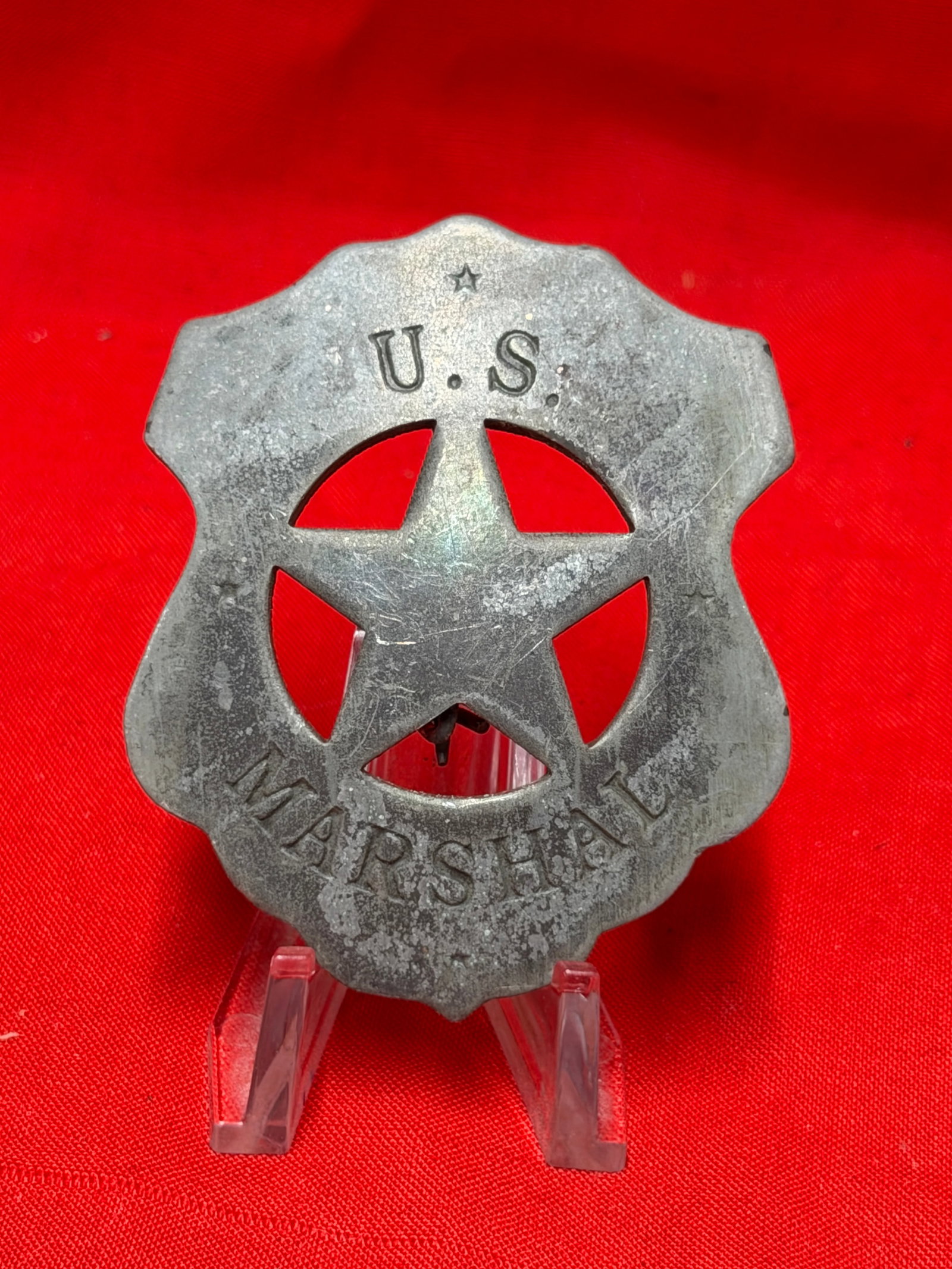 Vintage U.S. Marshal Star Badge Law Enforcement Shield Badge: Vintage U.S. Marshal style star badge featuring large cutout five point star design with “U.S. MARSHAL” lettering across the shield. Silver tone metal construction with pinback attachment on r