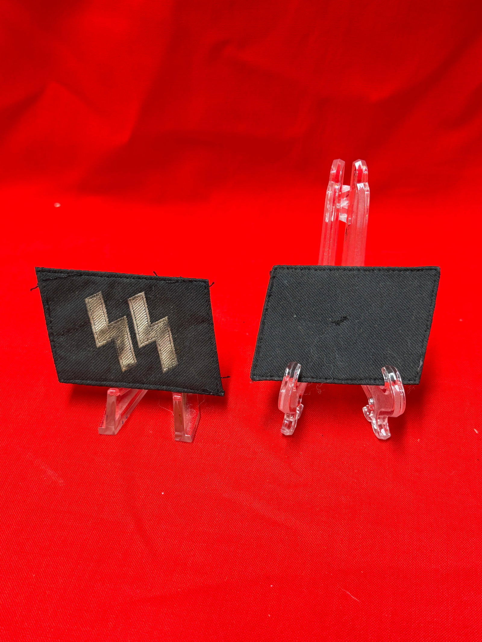 Pair of German WWII Style Black Collar Tabs with Silver SS Runes: Matching pair of black cloth collar tabs featuring silver embroidered double-rune style insignia on the front with stitched edging and backing material visible on the reverse. Tabs show handling wear,