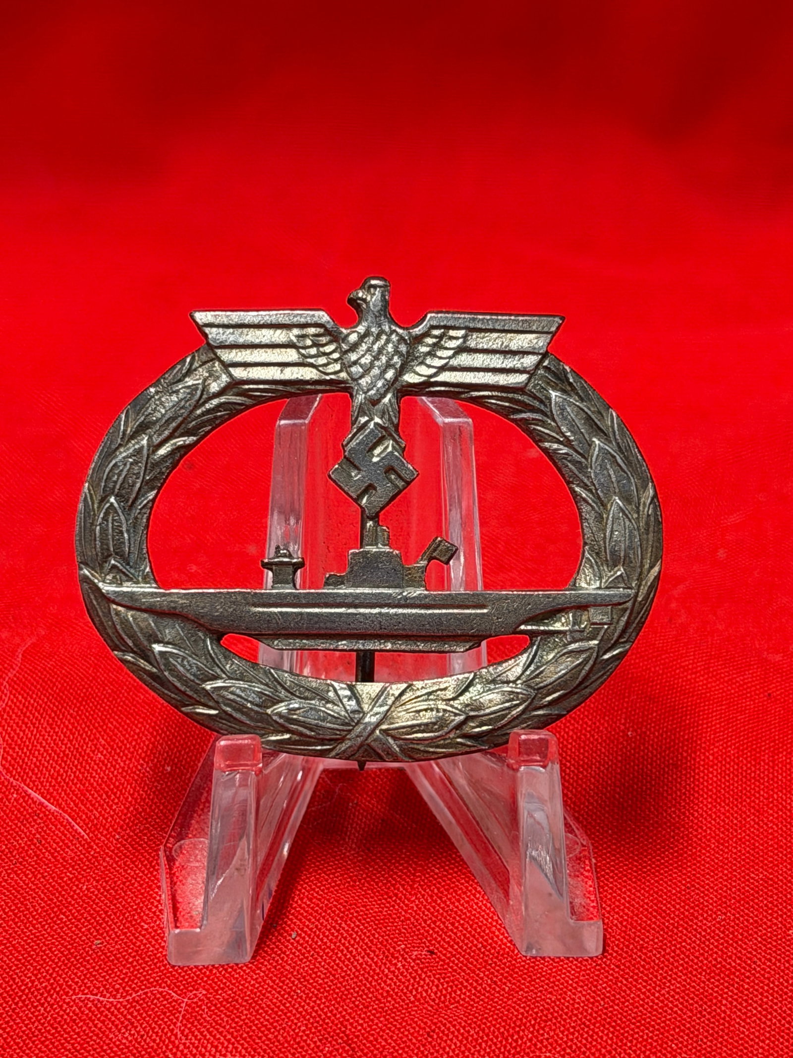 WWII German Kriegsmarine U-Boat War Badge: Metal naval-style badge featuring submarine design within oak leaf wreath and eagle motif at top. Reverse retains vertical pinback assembly. Item shows surface wear, patina, oxidation, and age-related
