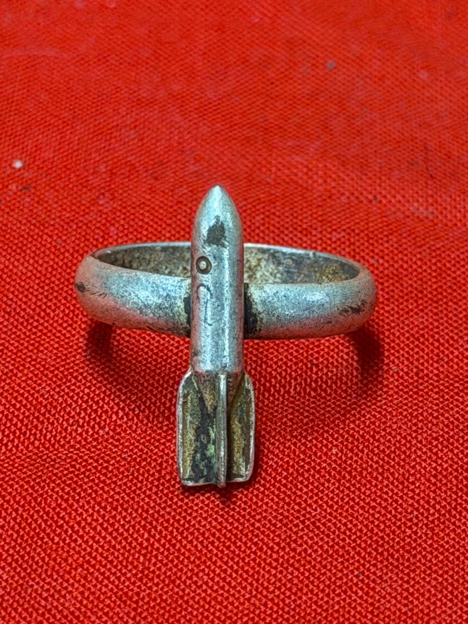 WW2 German Luftwaffe Trench Art Bomber Pilots Ring: WW2 German Luftwaffe themed trench art ring featuring a miniature aerial bomb mounted across a plain band. In our opinion, this piece appears to be a period theater-made or soldier-made item likely as