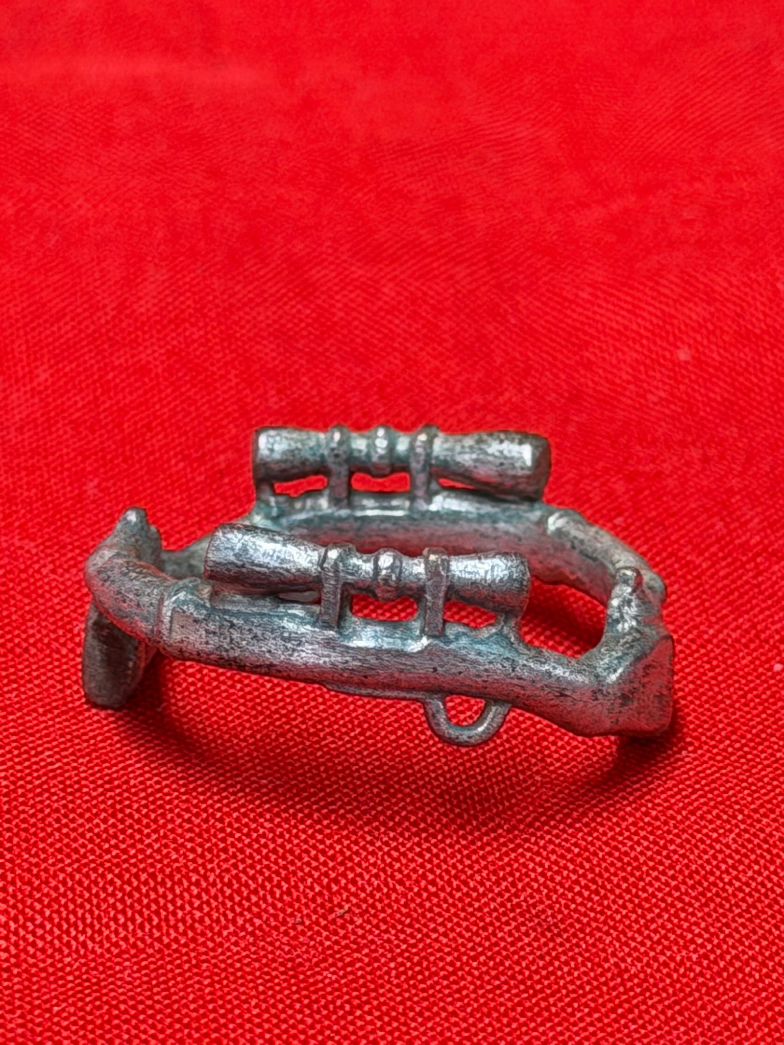 German WWII Sniper Rifle Motif Ring Cast Metal Militaria Collectible: German WWII sniper ring featuring detailed raised rifle motifs around the band. The ring displays two rifles with scope details integrated into the circular design. Made of silver-tone cast metal with