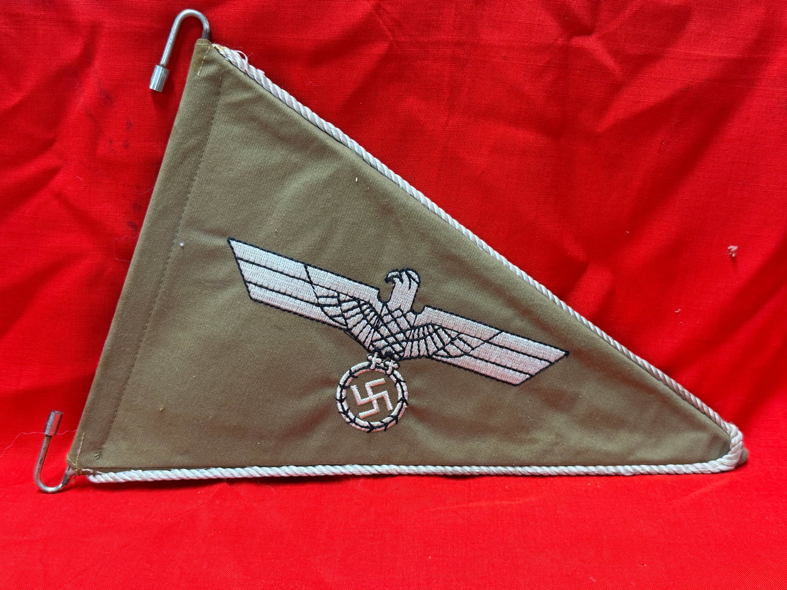 WW2 German Afrika Korps Vehicle Pennant Banner: WW2-era German Afrika Korps triangular vehicle pennant banner featuring embroidered eagle and swastika insignia on olive/tan cloth background with white twisted edge cord trim. Double-sided constructi
