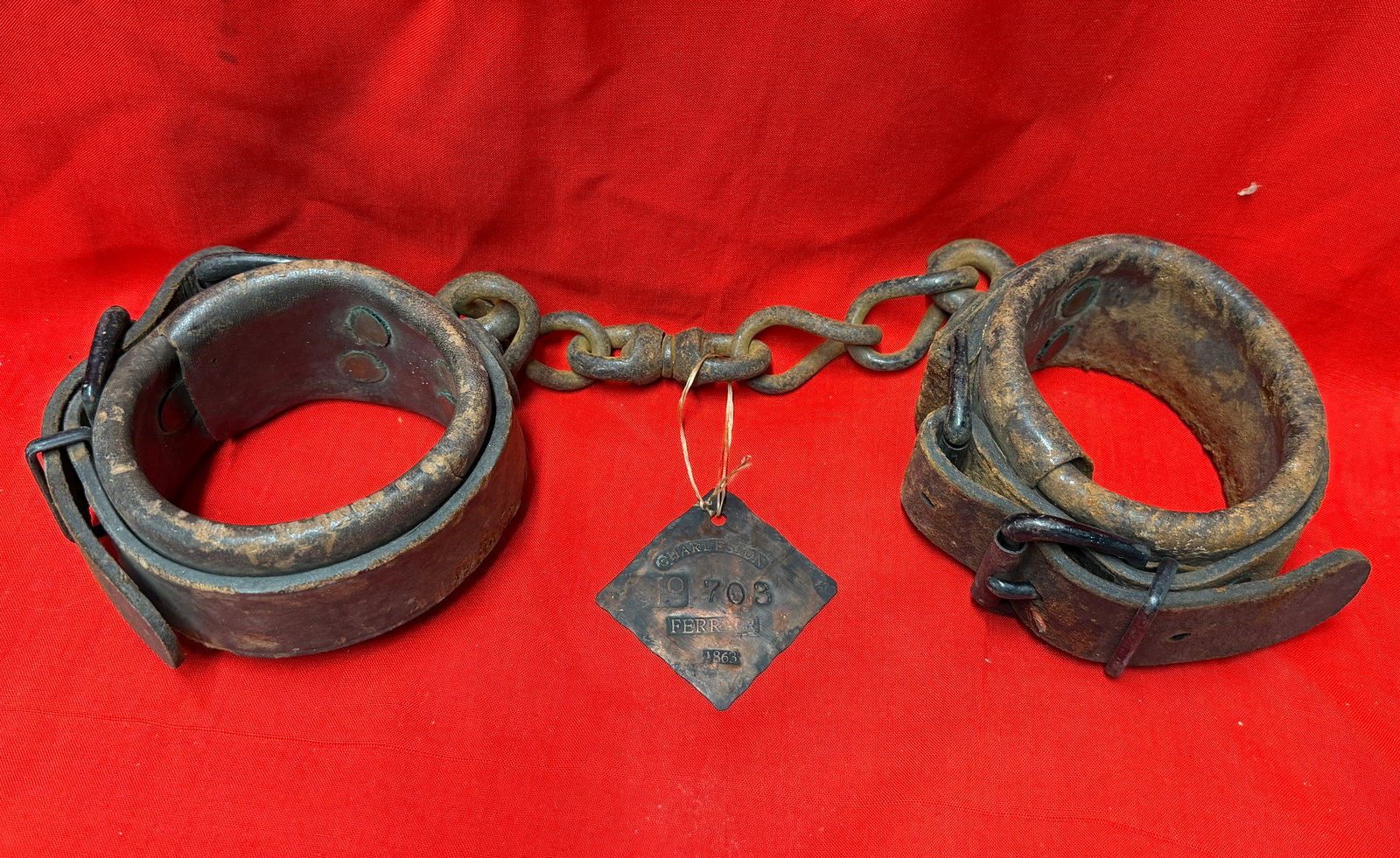 Civil War Charleston Ferry Prisoner Transport Slave Tag Shackles Dated 1863: Civil War-era iron restraint shackles with attached identification tag marked “CHARLESTON FERRY 1863” and numbered “703.” This rare set features heavy iron wrist restraints connected b
