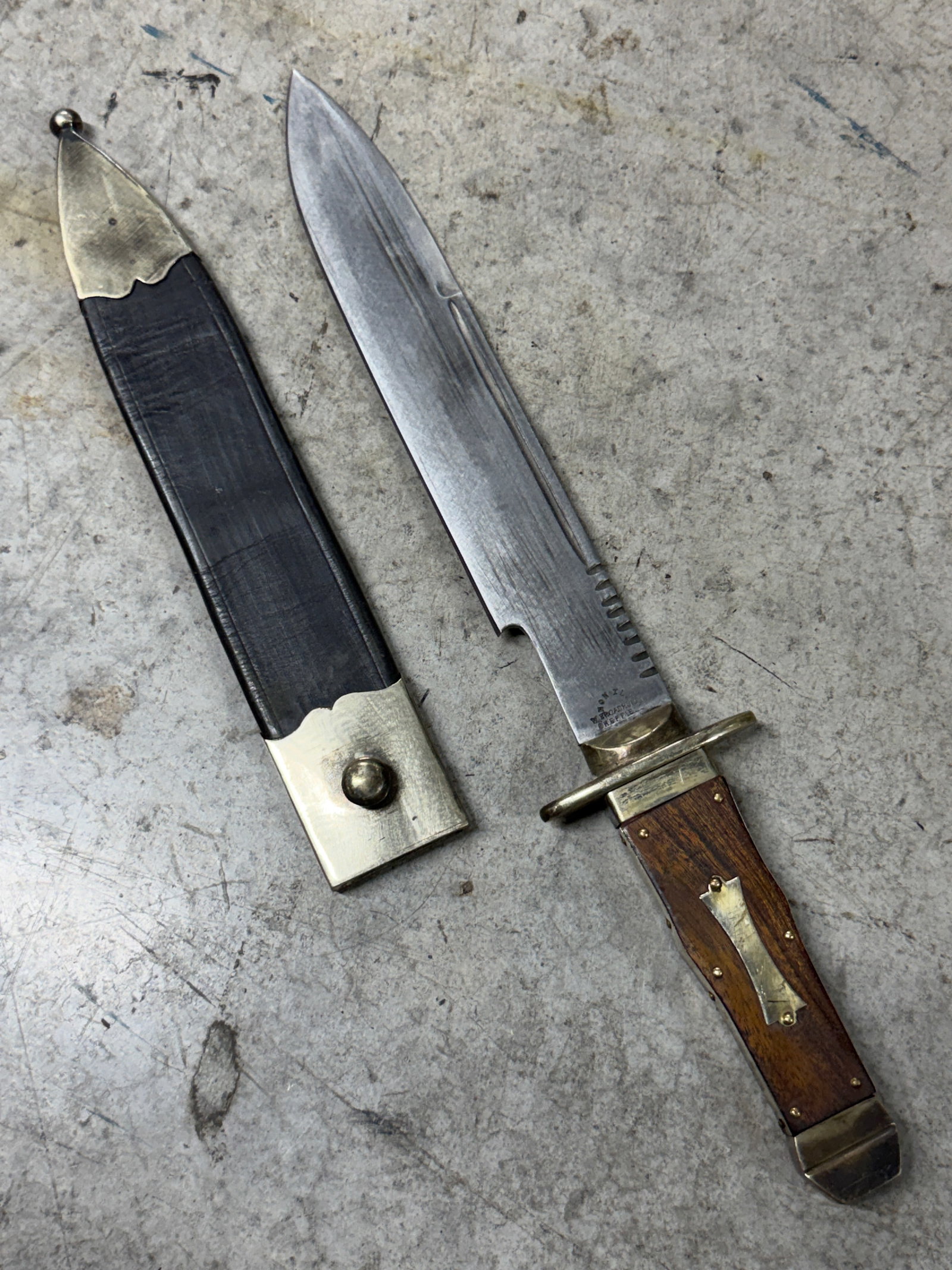 19th Century W. Broadhurst Sheffield Bowie Knife with Scabbard: 19th century Bowie knife by W. Broadhurst of Sheffield features a heavy clip point steel blade with decorative fuller and file work along the spine, retaining its original brass mounted leather scabba