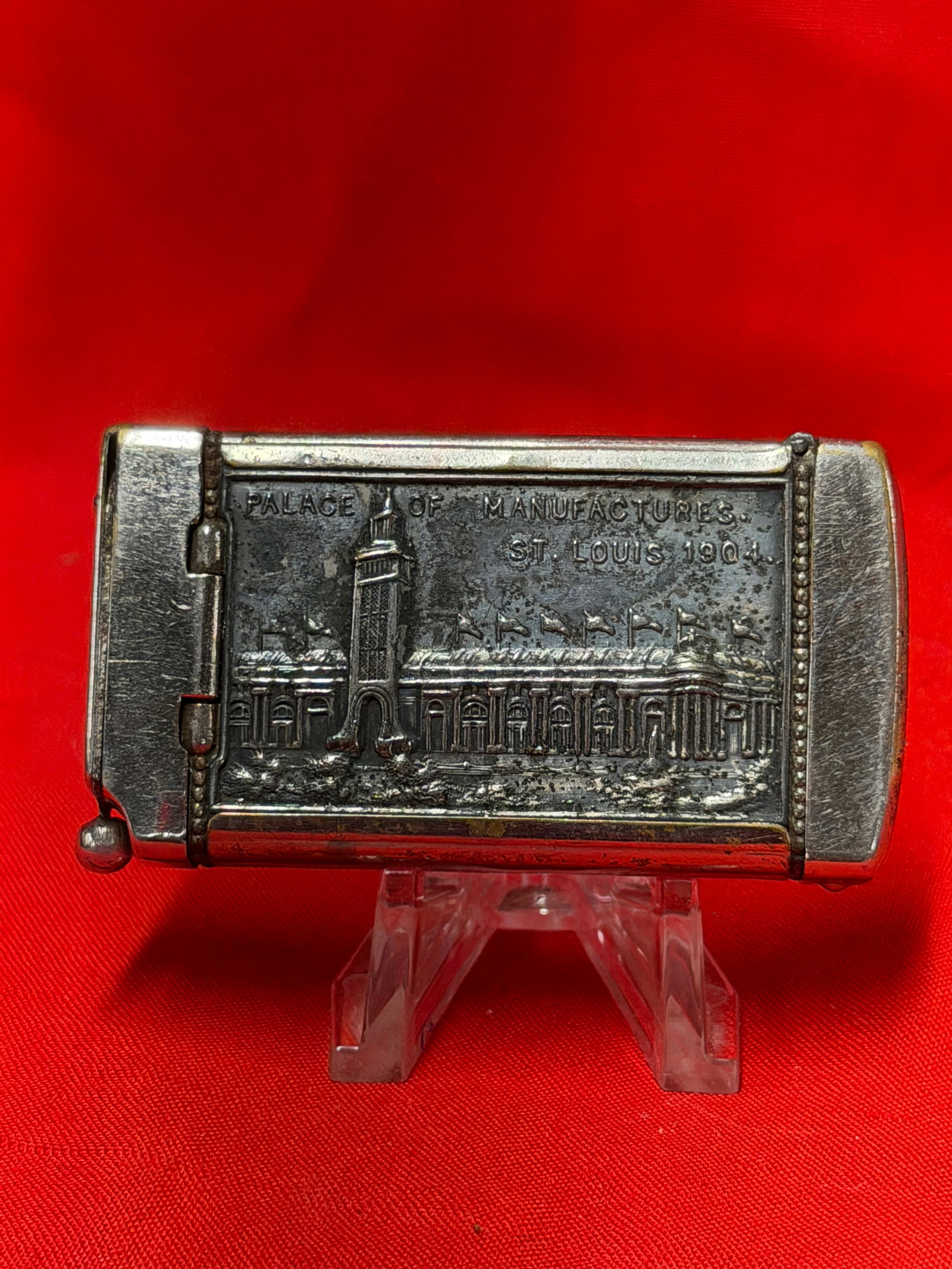 1904 St. Louis Worlds Fair Palace Of Manufactures Advertising Match Safe Holder: Metal match safe or match holder featuring raised scenes marked “Palace Of Manufactures St. Louis 1904” and “Palace Of Mines And Metallurgy” from the 1904 St. Louis World’s Fair. Hin