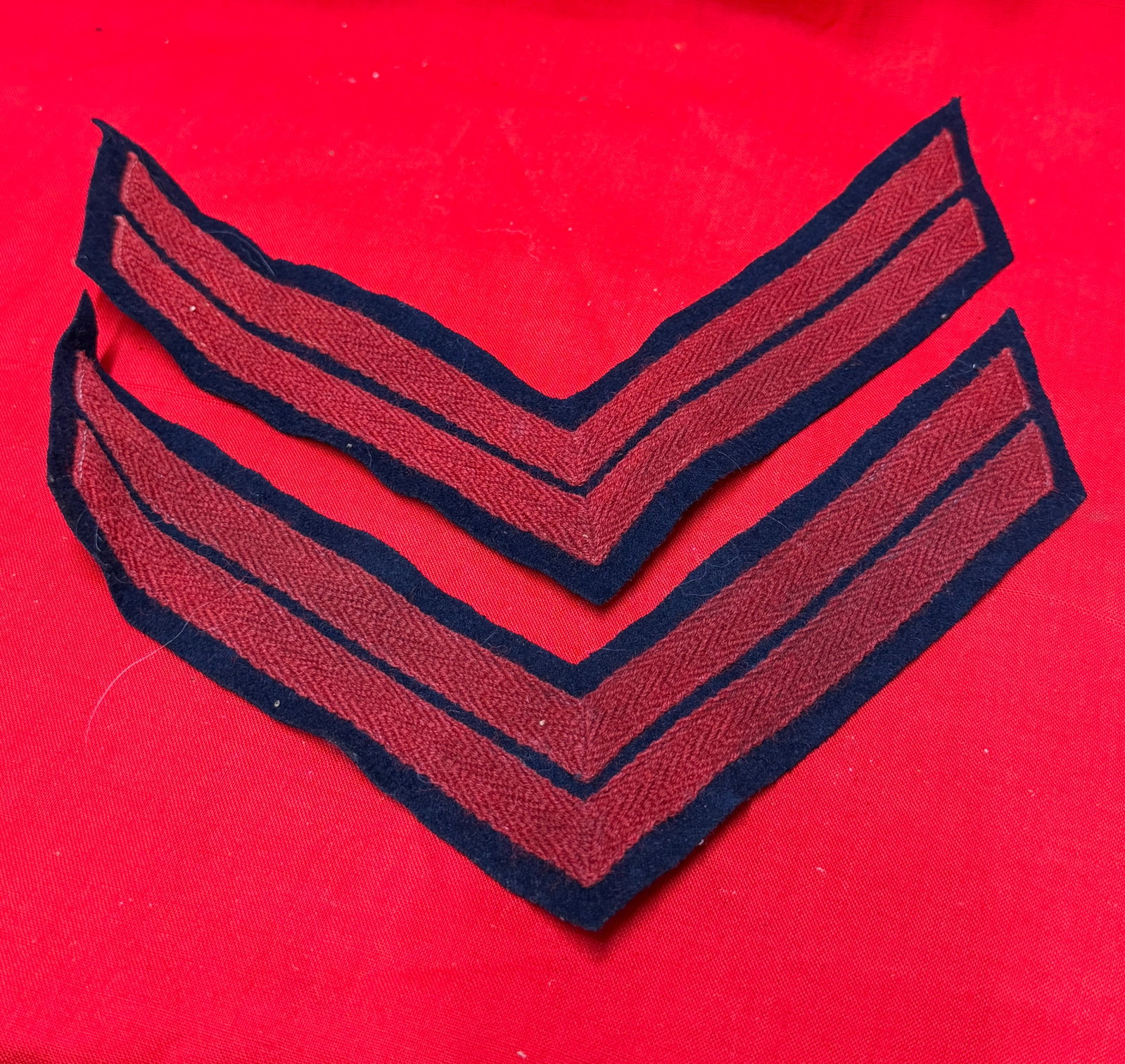 Civil War Era Red Wool Uniform Sergeant Chevrons Sleeve Rank Insignia Pair: Civil War era military uniform sleeve chevrons consisting of a matching pair of red wool rank insignia on dark blue wool backing. These V-shaped stripes were worn on uniform sleeves to denote non-comm