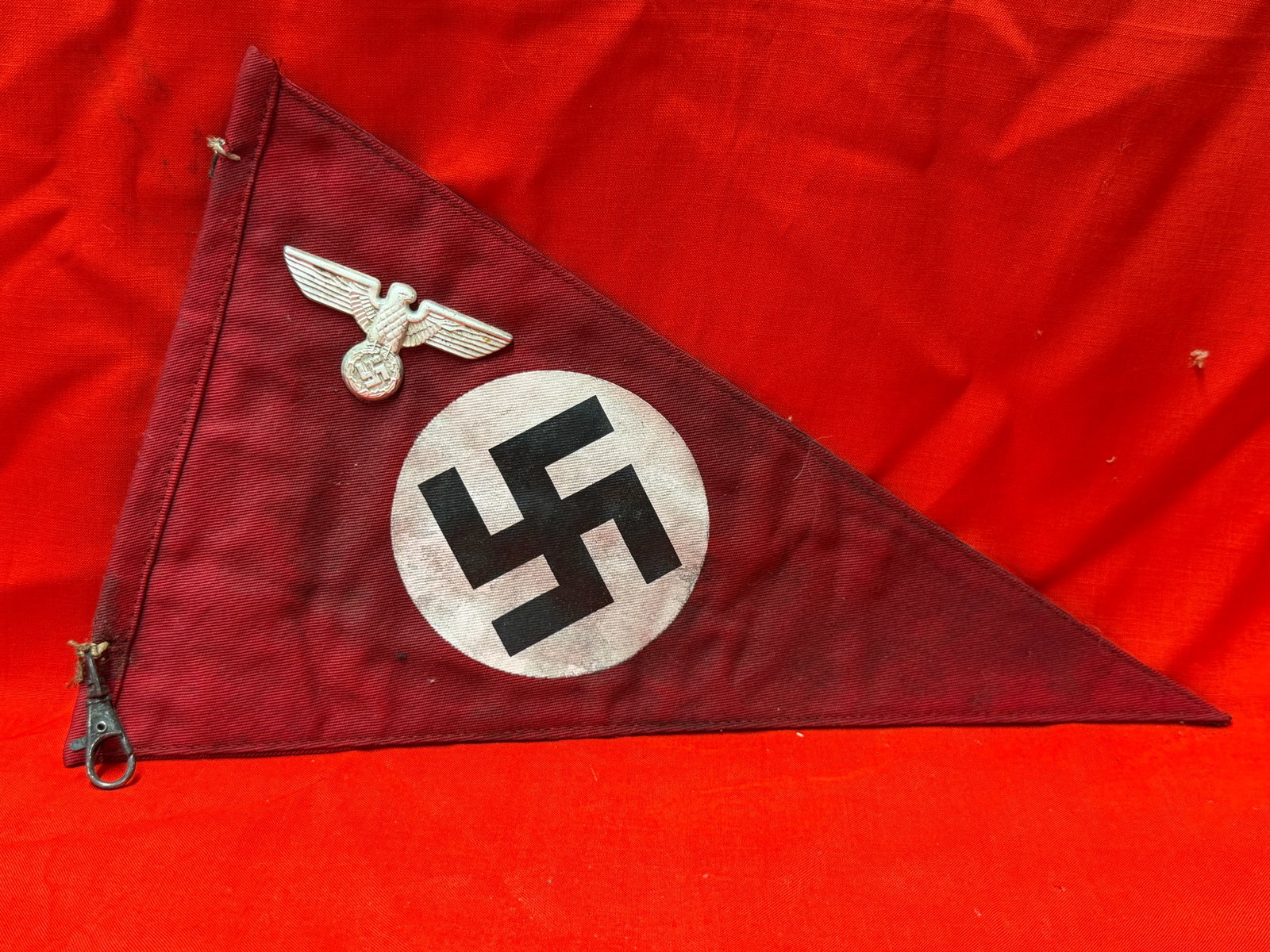 WWII German NSDAP Pennant Banner With Eagle Badge Political Flag Display: WWII German NSDAP triangular pennant banner featuring printed swastika emblem on red field with attached metal eagle insignia badge. In our opinion this piece displays characteristics associated with 