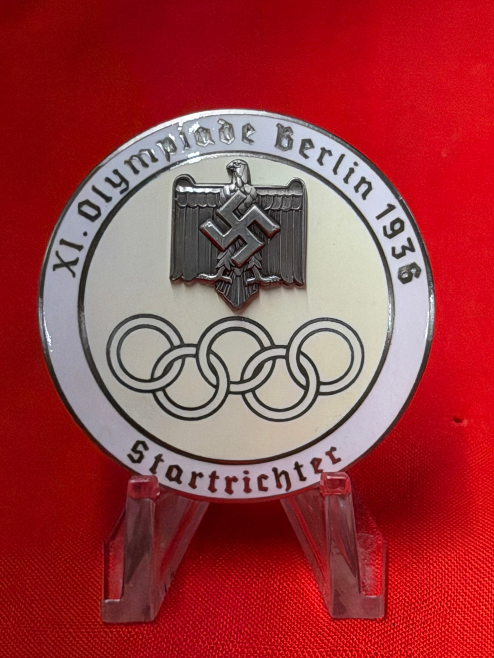 WW2 German XI Olympiade Berlin 1936 German Olympic Games Badge With Eagle and Rings Design: German XI Olympiade Berlin 1936 commemorative badge featuring raised eagle emblem above Olympic rings with “XI. Olympiade Berlin 1936” and “Startrichter” text around the border. Revers