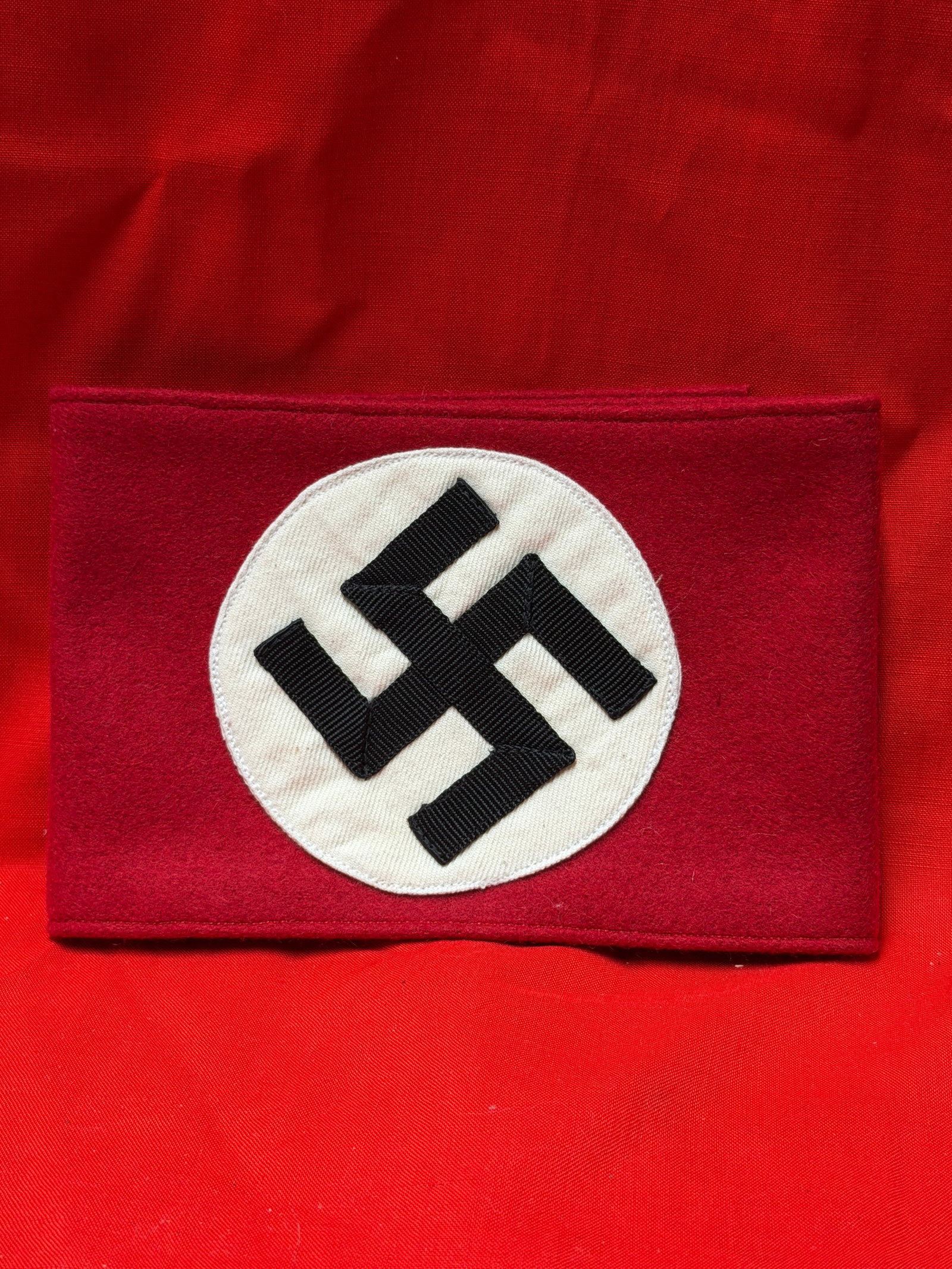 WW2 German Political Armband Red Wool Construction With Multi Piece Center Emblem: German political armband constructed from red wool material featuring centrally applied white roundel with black multi piece ribbon constructed emblem. Interior shows stitched circular reinforcement a