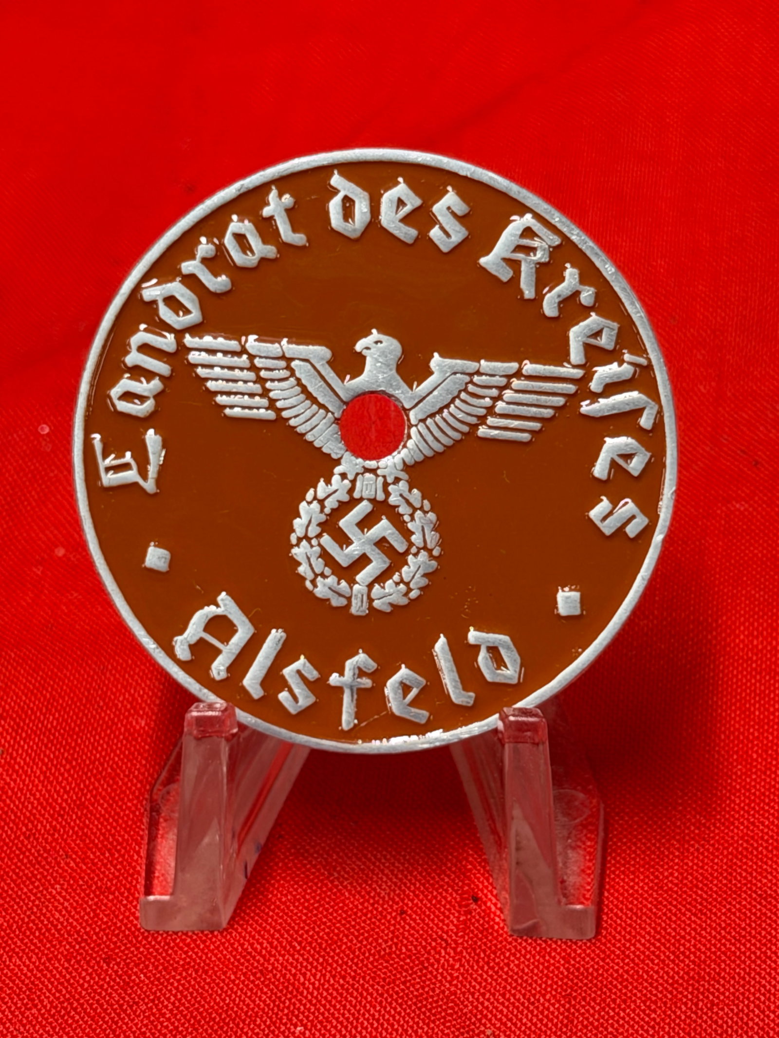 German NSDAP Kreis Alsfeld Tinnie Badge Brown Enamel Finish Political Rally Related: German NSDAP related tinnie badge featuring brown enamel style front with silver tone lettering, central eagle emblem, and Kreis Alsfeld inscription. Reverse shows plain metal backing with central mou