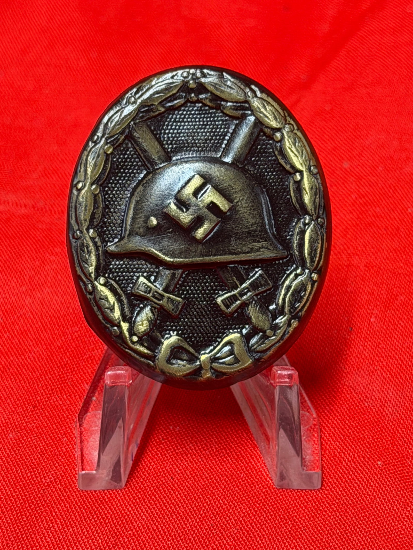 German WW2 Style Black Wound Badge Helmet & Crossed Swords Pin Back Badge: German WW2 style Black Wound Badge featuring steel helmet with swastika over crossed swords within an oval laurel wreath design. Dark finish front with highlighted details and traditional pin back att