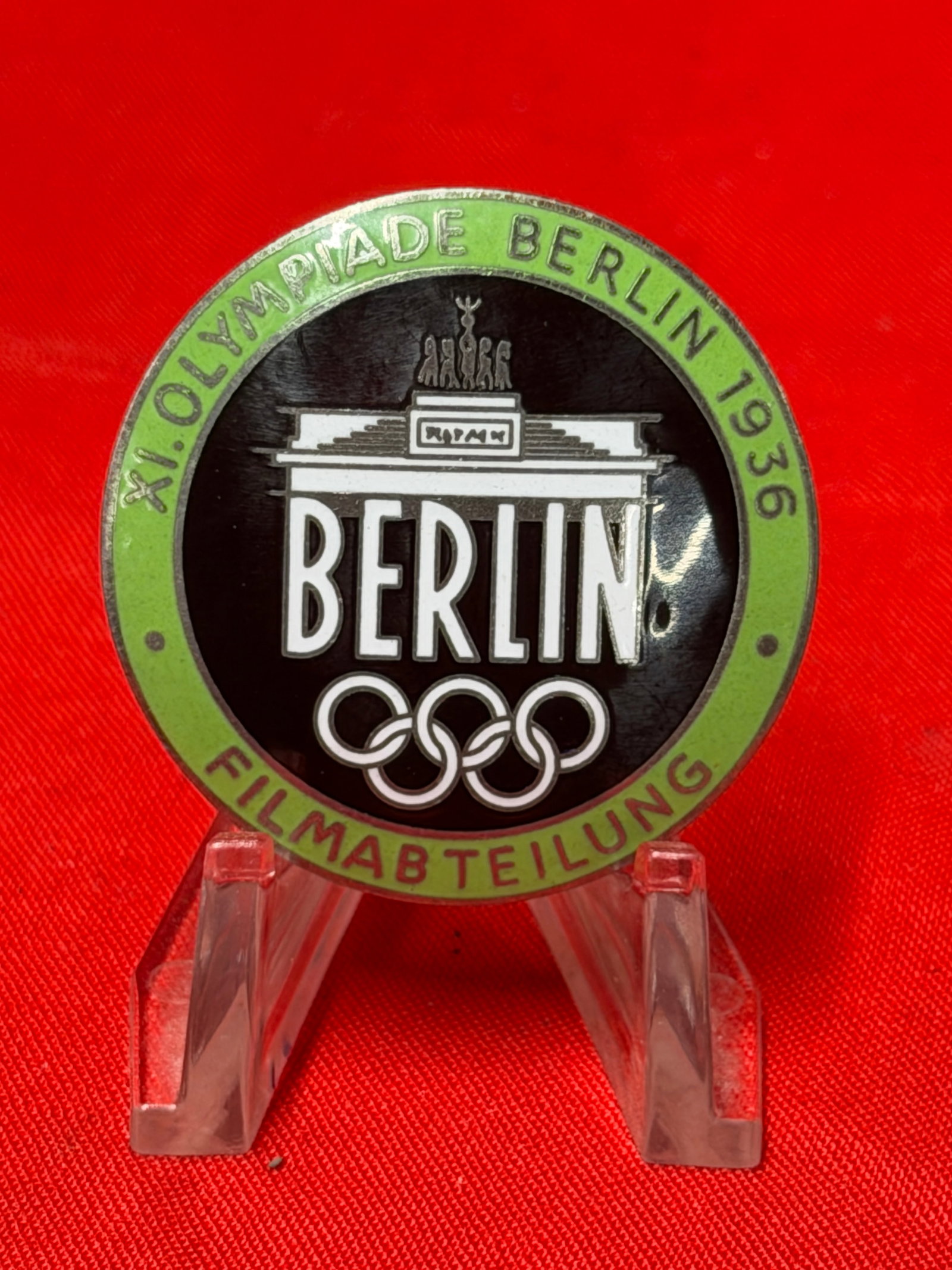 WW2 1936 Berlin Olympic Games Film Department Pin Badge – Rob. Neff Berlin: 1936 Berlin Olympic Games commemorative pin badge featuring the inscription “XI. Olympiade Berlin 1936” and “Filmabteilung” surrounding the Brandenburg Gate and Olympic rings design. T