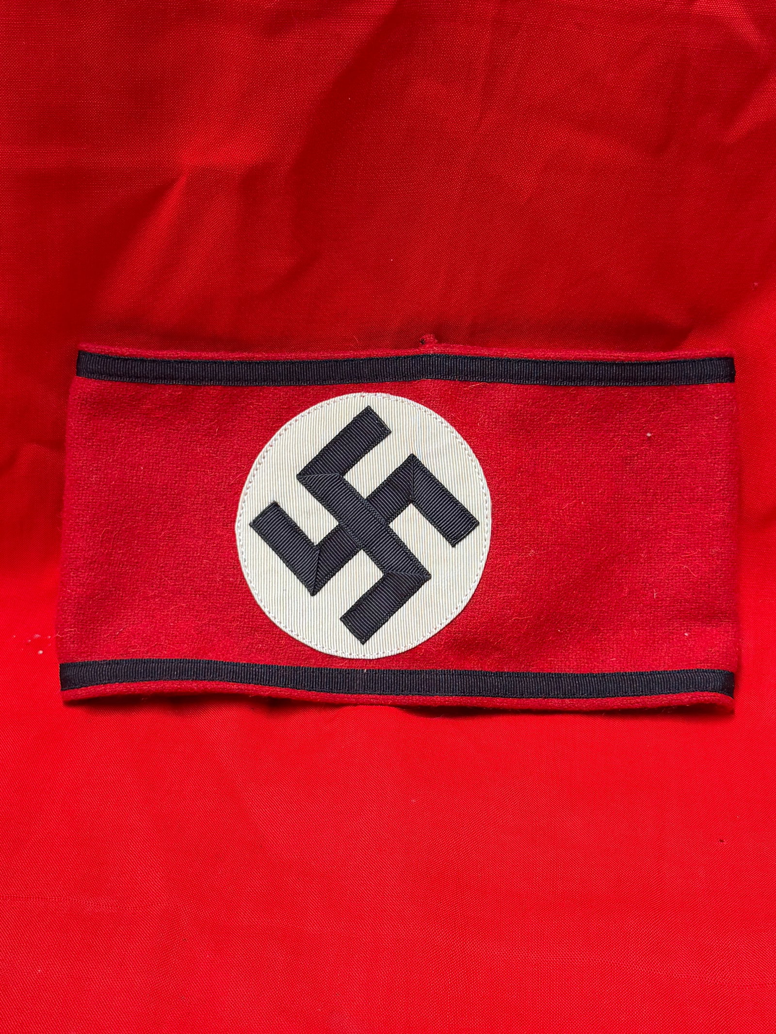 WWII German Waffen SS Officer Armband with Cloth RZM Tag: World War II German Waffen SS officer armband constructed of red wool fabric with black ribbed edge trim and sewn white roundel featuring an applied black swastika. Interior retains original cloth RZM