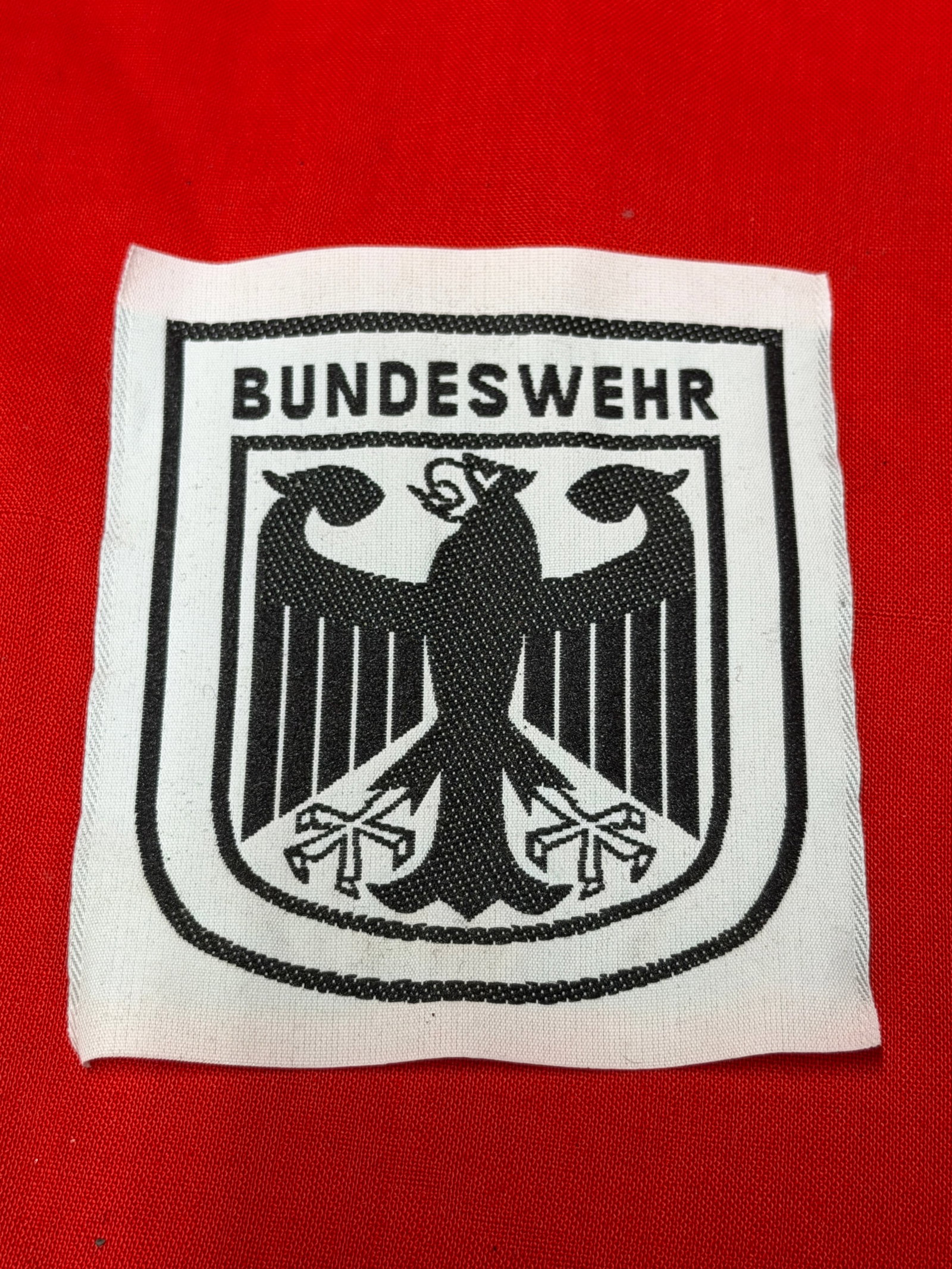 Bundeswehr Federal German Armed Forces Cloth Uniform Patch Insignia: Bundeswehr Federal German Armed Forces cloth insignia patch featuring black eagle national emblem and Bundeswehr text on white background. In our opinion this is a very interesting Cold War era German