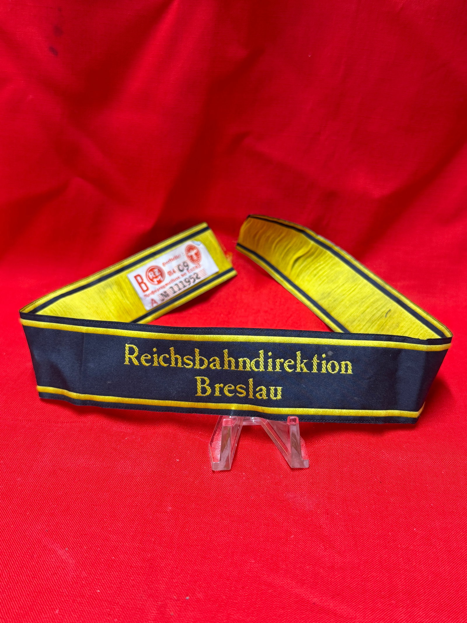 WWII German Reichsbahn Directorate Breslau Armband / Cuff Title – RZM Tagged: WWII German Reichsbahn (German State Railway) cuff title / armband section embroidered “Reichsbahndirektion Breslau” in gold lettering on dark navy backing with yellow borders. Interior retain