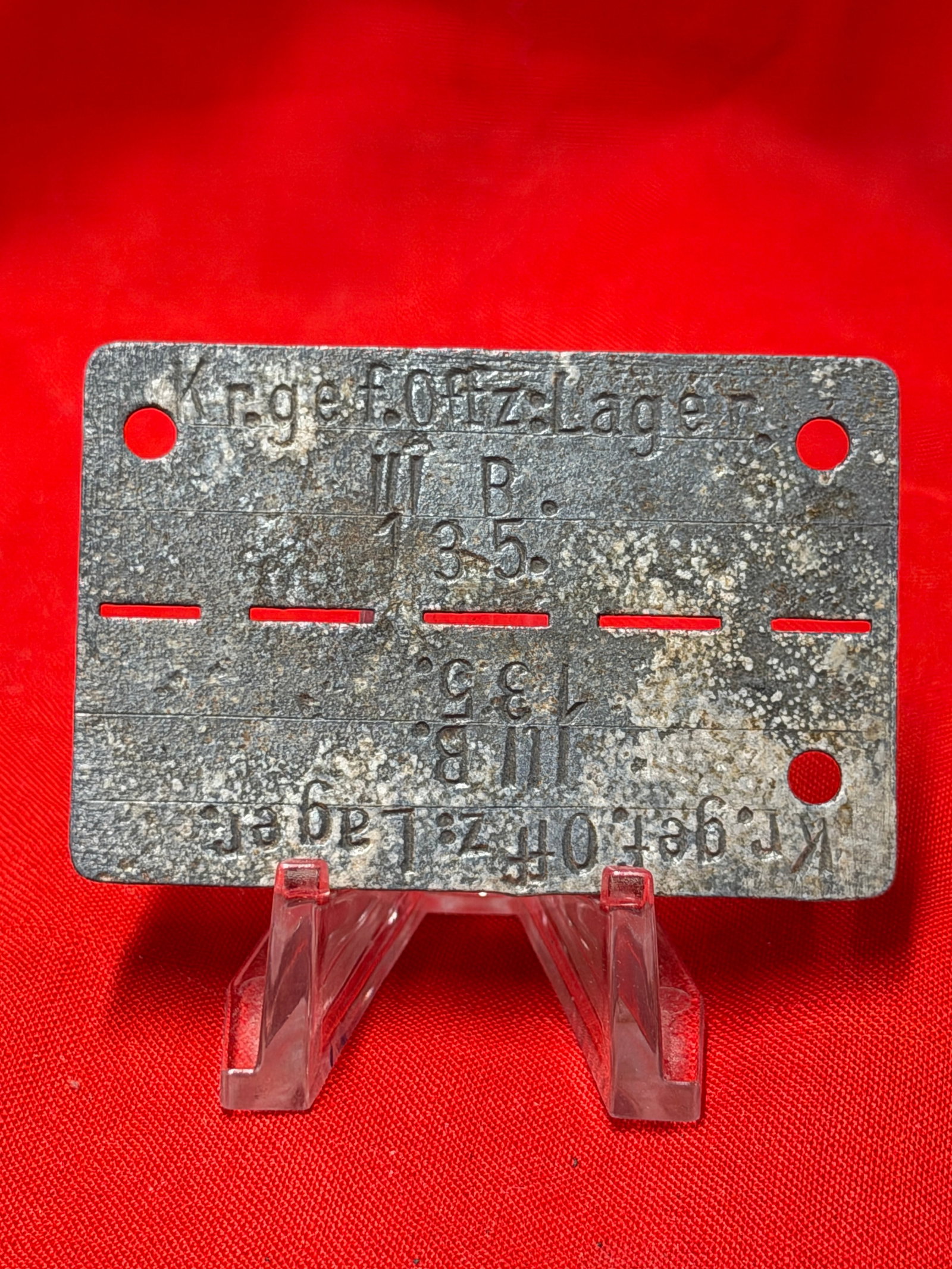 WWII German POW Identification Tag – Kriegsgefangenenlager III B / Oflag Prison Camp ID Disc: WWII German prisoner-of-war identification tag (dog tag style) stamped “Kriegsgefangenenlager III B” with prisoner number markings “135” and additional camp designations visible. Const