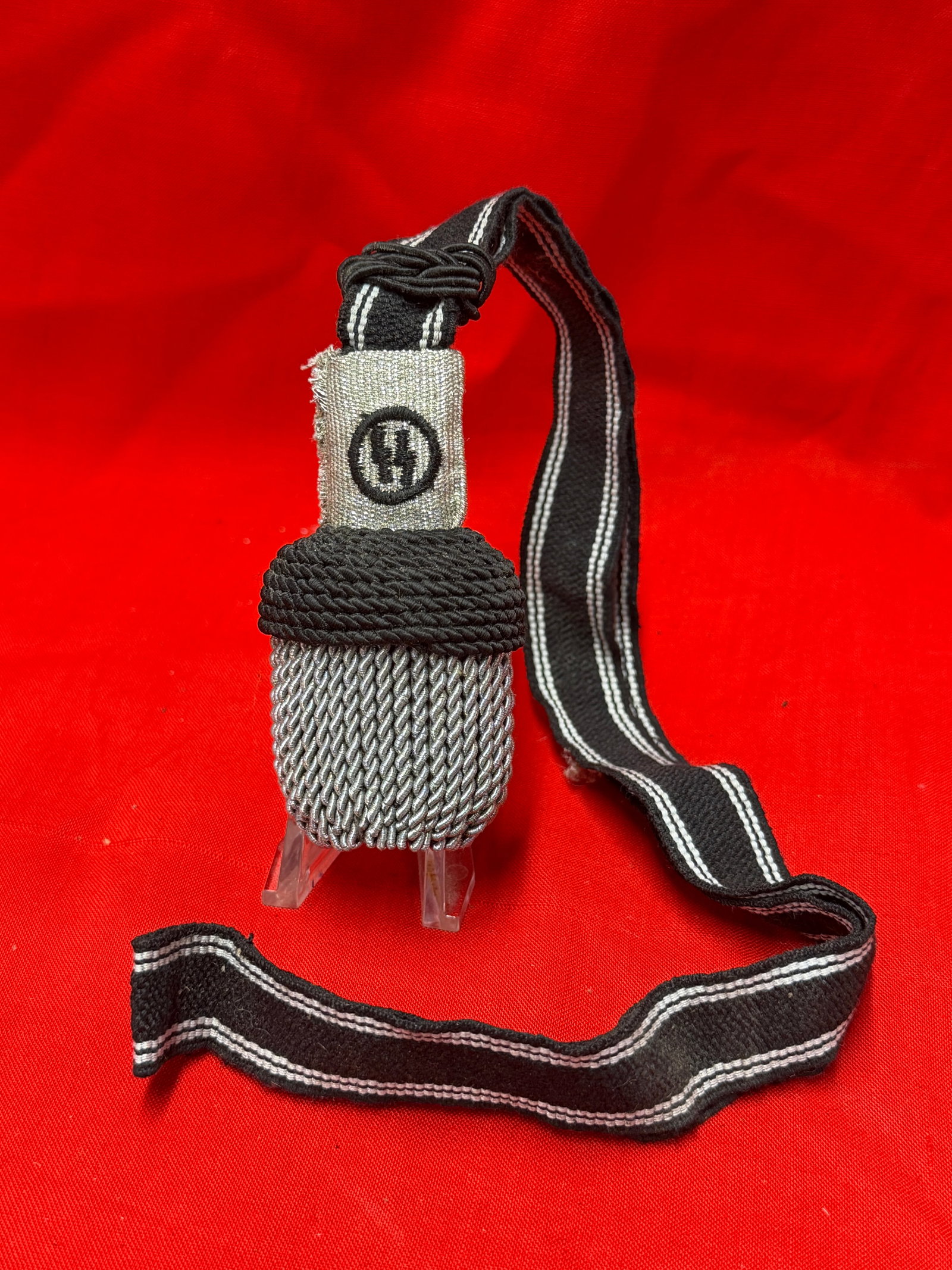 WWII German SS Dress Uniform Sword Knot / Portepee: WWII German SS portepee (sword knot) constructed with silver aluminum wire bullion and black woven cord suspension strap. The upper slide features an embroidered SS runic insignia on silver-gray fabri