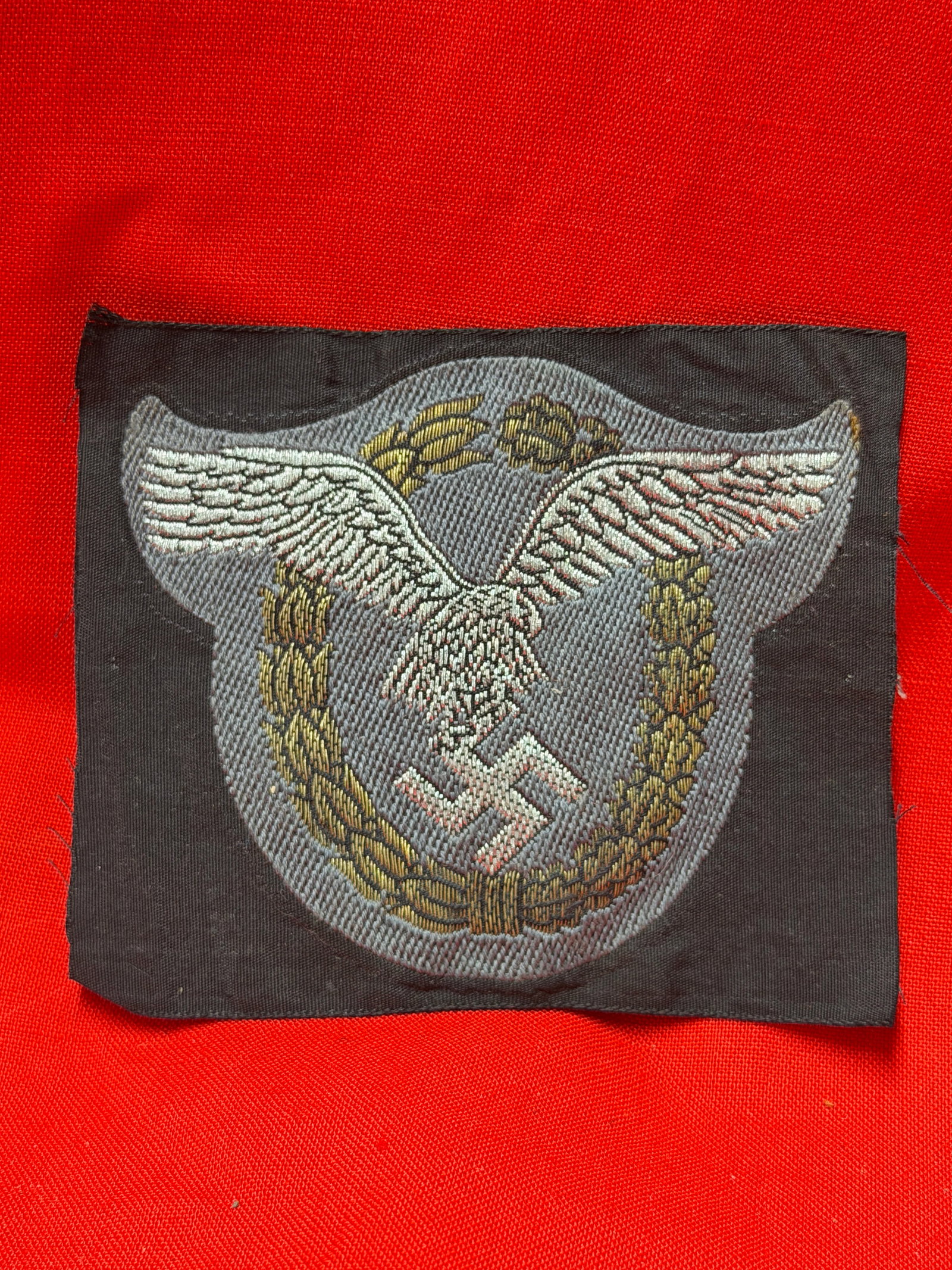 WWII German NSDAP Political Visor Cap Wreath & Eagle Insignia Patch: WWII German NSDAP political visor cap insignia patch featuring the national eagle above oak leaf wreath with central swastika. Multi-color machine embroidered construction on dark backing cloth, consi