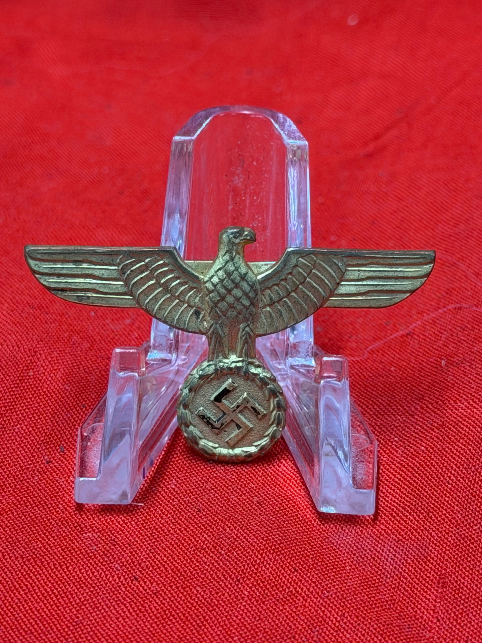 WWII German NSDAP Political Leader Visor Cap Eagle Insignia – Gold Gilt Metal Pin: WWII era German NSDAP Political Leader visor cap eagle insignia constructed in gold gilt metal with horizontal pinback attachment on the reverse. Features the spread-wing eagle clutching a wreath with