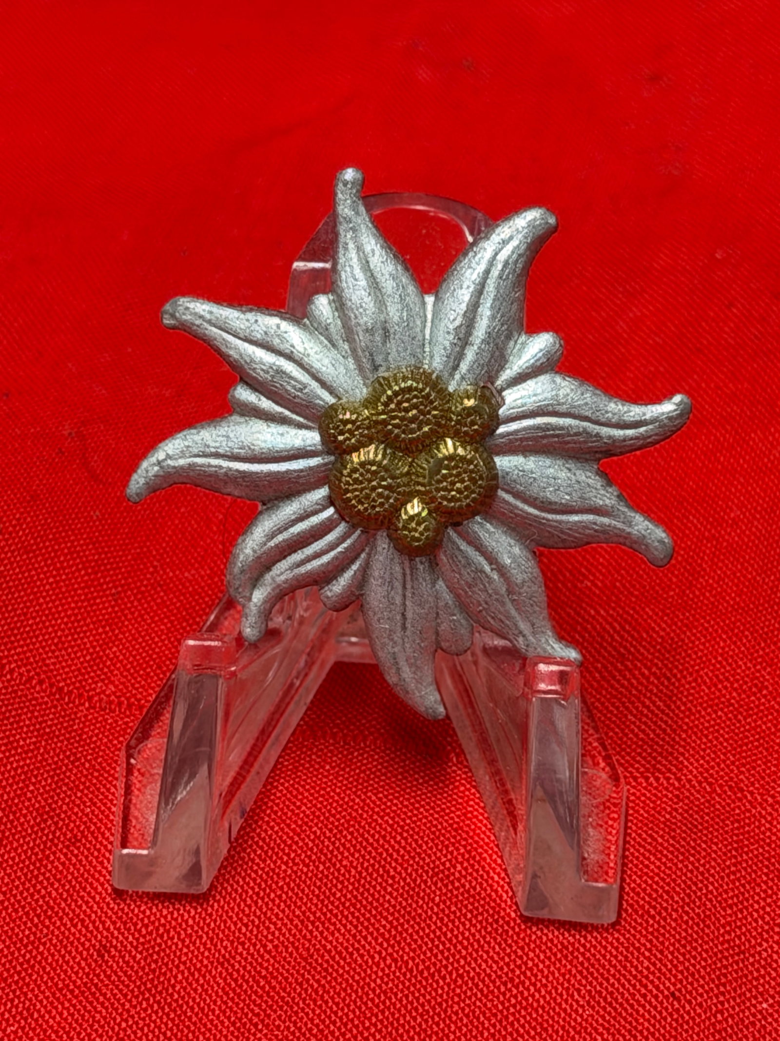 WWII German Edelweiss Mountain Troops Cap Badge – Gebirgsjäger Insignia Pin: WWII era German Edelweiss badge associated with Gebirgsjäger (Mountain Troops) uniforms and headgear. Features detailed silver-tone Edelweiss flower petals with textured gold-tone center cluster and 