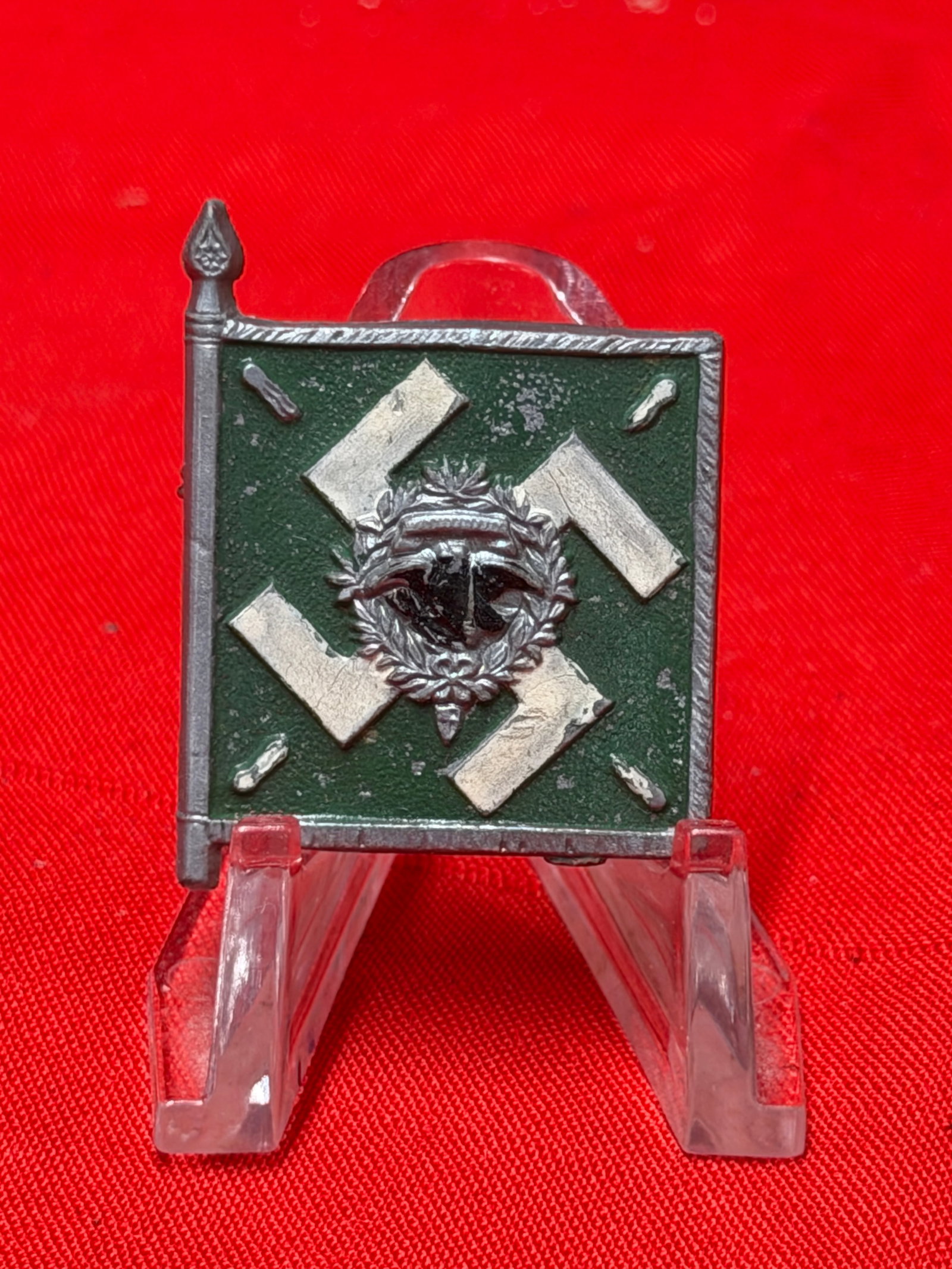 WWII German Regiment General Göring Tinnie / Badge – Flag Design: WWII-era German commemorative tinnie featuring a green flag design with silver swastika and central wreath emblem. Reverse is marked “REGIMENT GENERAL GÖRING,” referring to the elite Hermann 