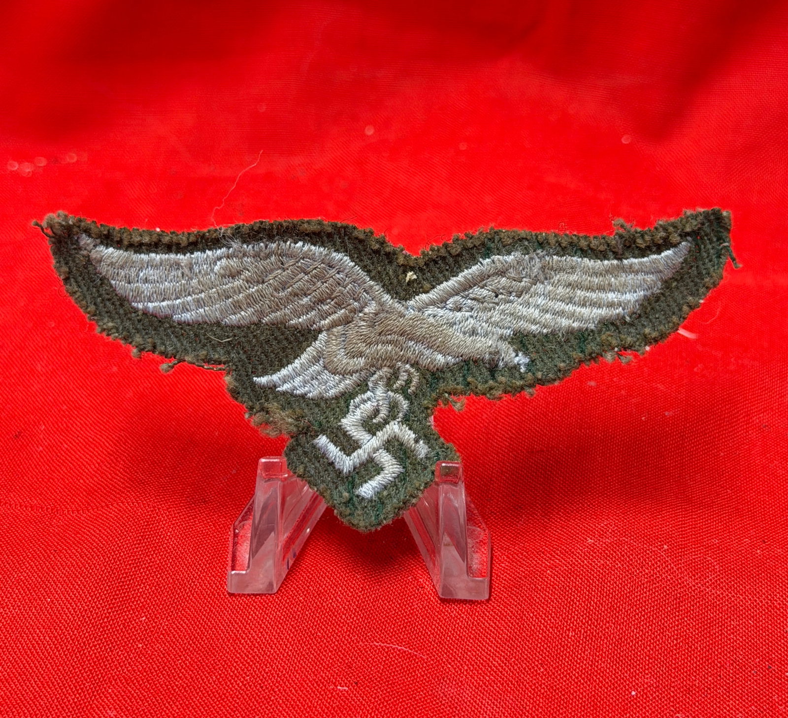 WWII German Army Heer BeVo Style Eagle Breast Insignia Patch: World War II German Heer (Army) eagle breast insignia patch featuring silver-gray embroidered eagle clutching swastika on dark field-gray wool backing. Period machine-embroidered construction with vis