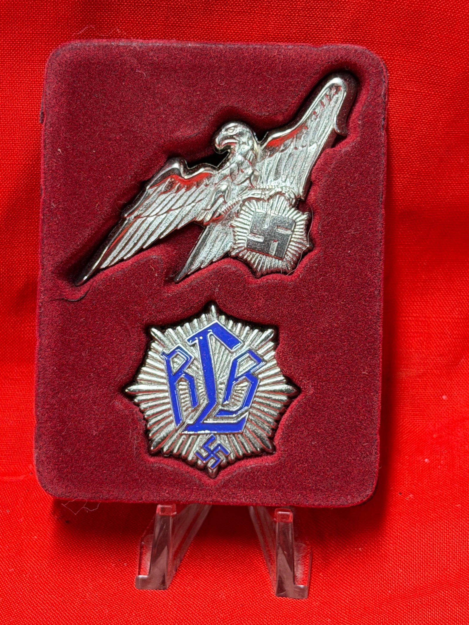 WWII German RAD Badge and Eagle Pin Set Display: This Second World War German RAD related badge and eagle pin set is mounted in a fitted red velvet style display case. The set includes a silver tone eagle insignia and a blue enamel RAD marked badge 