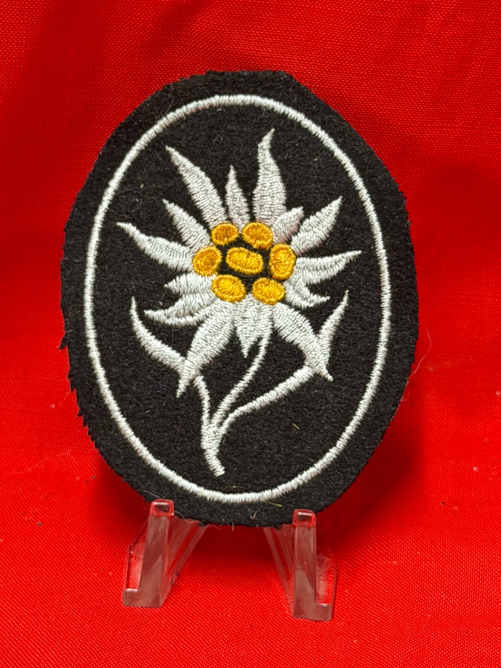 WWII German Waffen SS Mountain Troops Edelweiss Cloth Sleeve Patch: This Second World War German mountain troops Edelweiss cloth sleeve patch features detailed white and yellow embroidery on a black wool backing. The oval shaped insignia displays the traditional Edelw