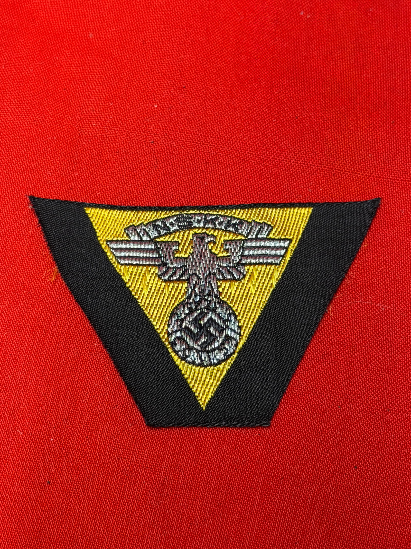 WWII German NSKK (National Socialist Motor Corps) Cap Insignia Patch – Machine Embroidered: WWII era German NSKK (Nationalsozialistisches Kraftfahrkorps / National Socialist Motor Corps) machine-embroidered cap insignia patch featuring the NSKK-style eagle clutching a wreathed swastika embro