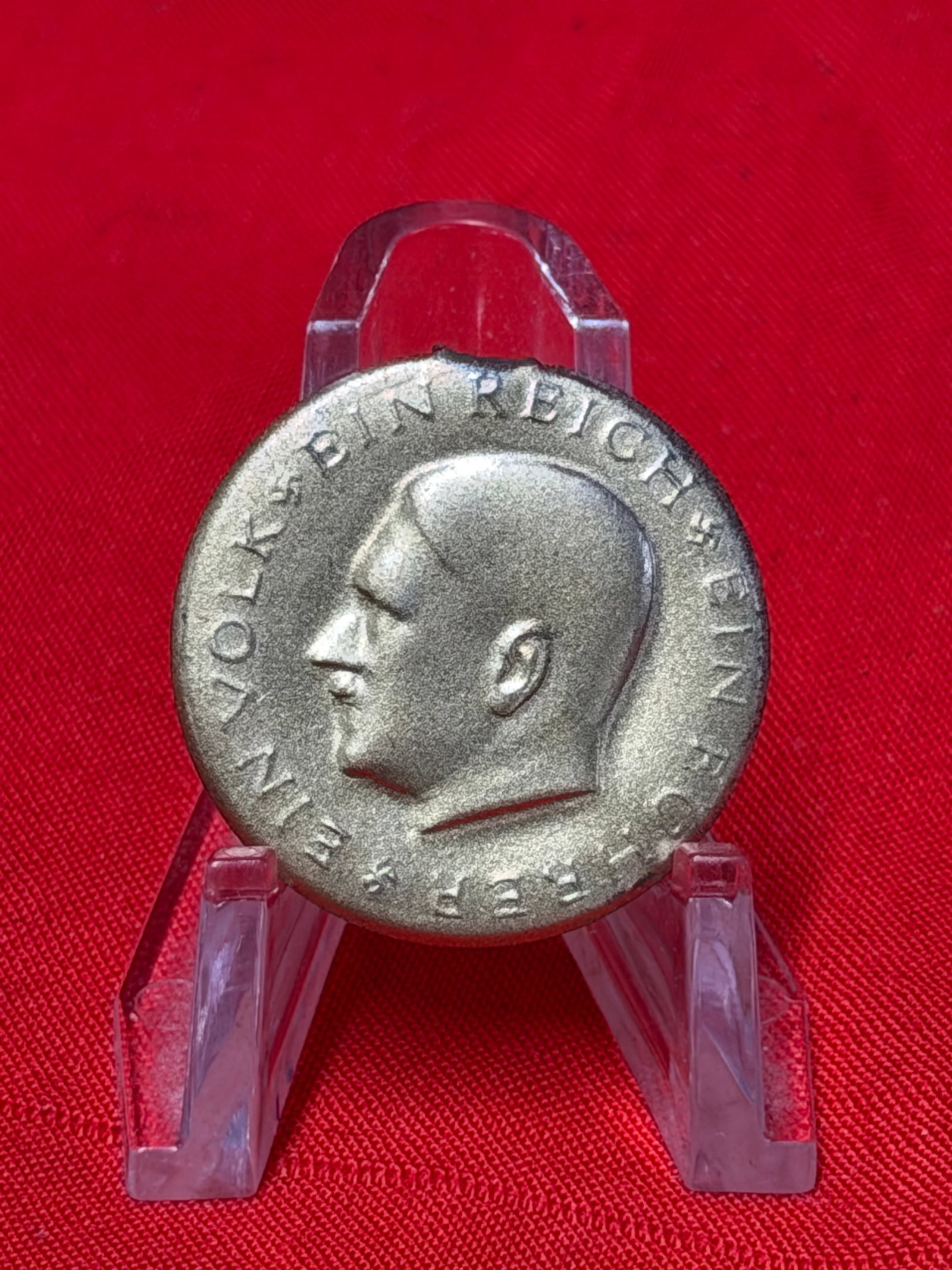 WWII German Third Reich Adolf Hitler Commemorative Tinnie Pin Badge: WWII era German Third Reich commemorative tinnie pin featuring profile portrait of Adolf Hitler with surrounding German text. Reverse retains original vertical pinback assembly. Constructed of silver-