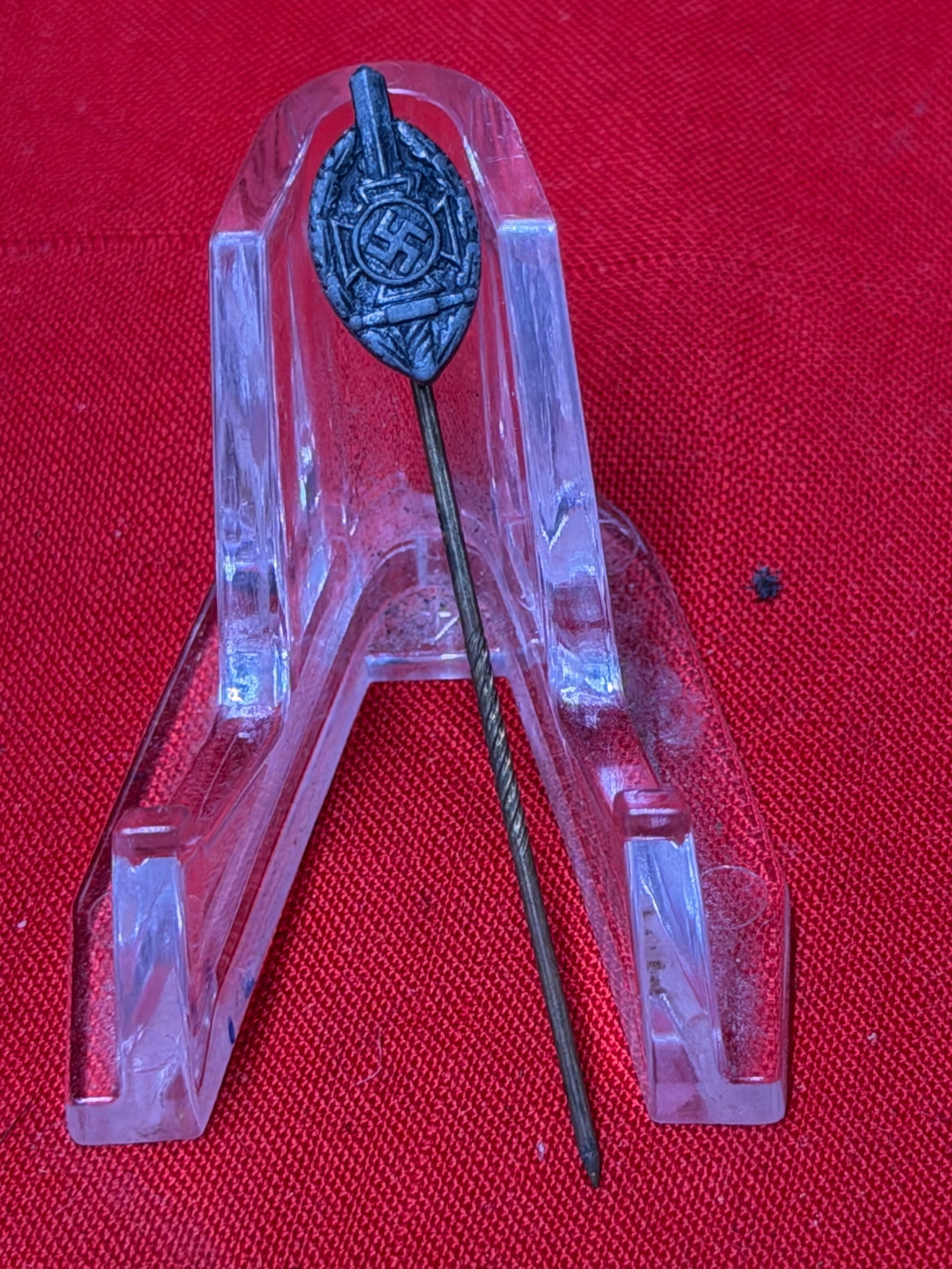 WWII German NSKOV National Socialist War Victim’s Care Stick Pin: World War II era German NSKOV (National Socialist War Victim’s Care) themed stick pin featuring oval badge design with central swastika emblem and surrounding wreath motif. In our opinion, the piece