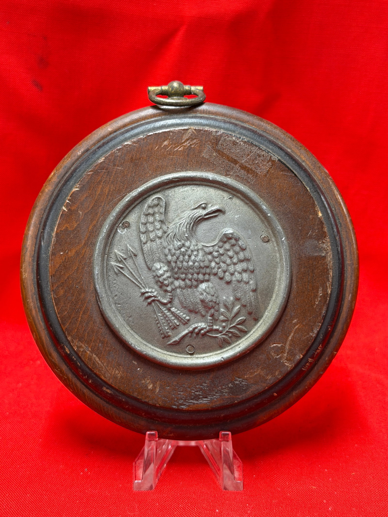Peter Roberts Colonial Craftsman U.S. Military Eagle Wall Plaque Circa 1855-1861: Round wooden wall plaque featuring raised U.S. military eagle emblem with arrows and olive branch design. Back retains Peter Roberts Colonial Craftsman label marked “U.S. Military Eagle Circa 1855-1