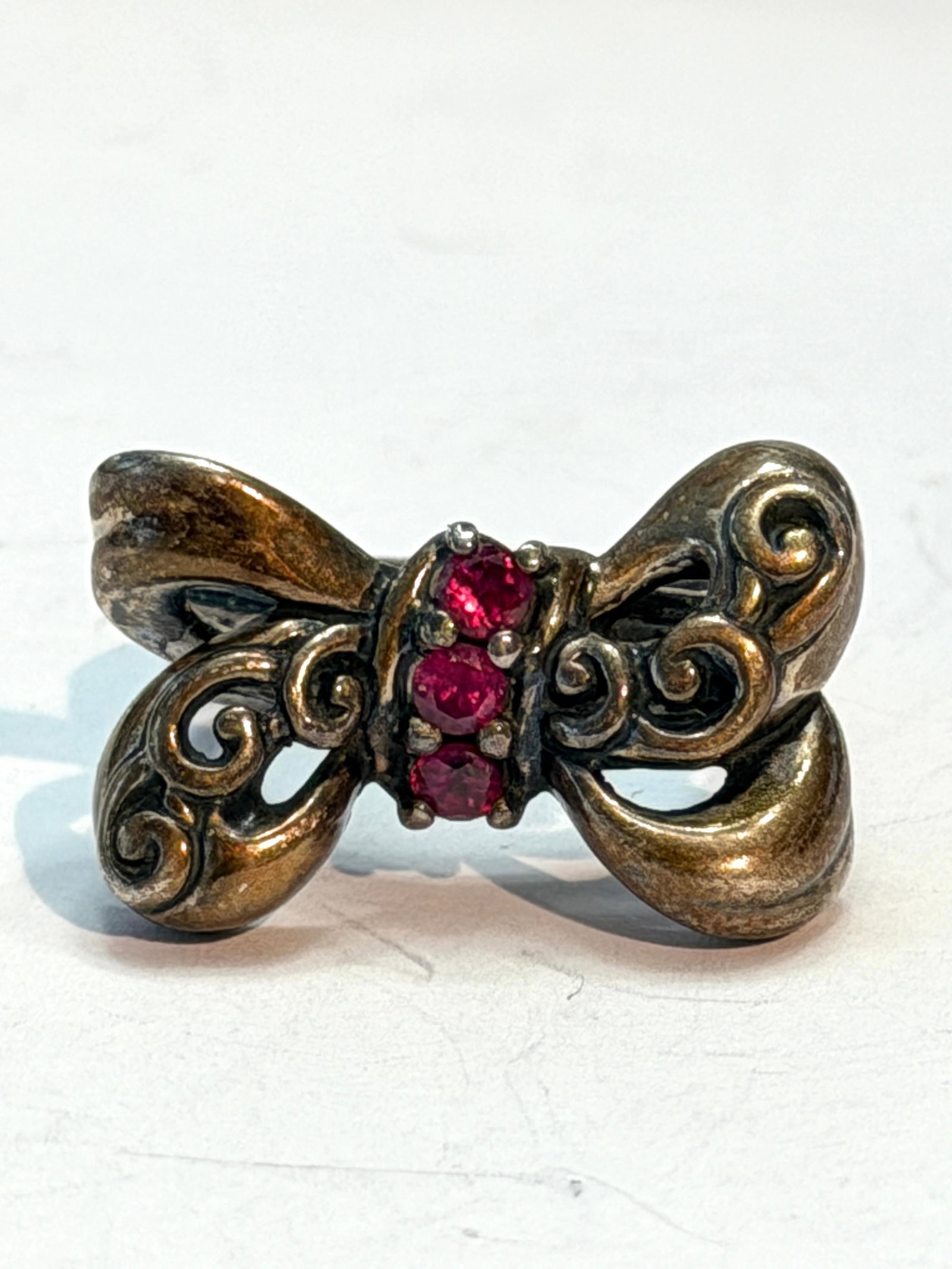 Vintage Sterling Silver Bow Ring with Red Rhinestones Size 7: Vintage sterling silver bow ring featuring an ornate openwork ribbon design accented with three vibrant red rhinestones at the center. Elegant scrolling details and oxidized patina give this piece a c
