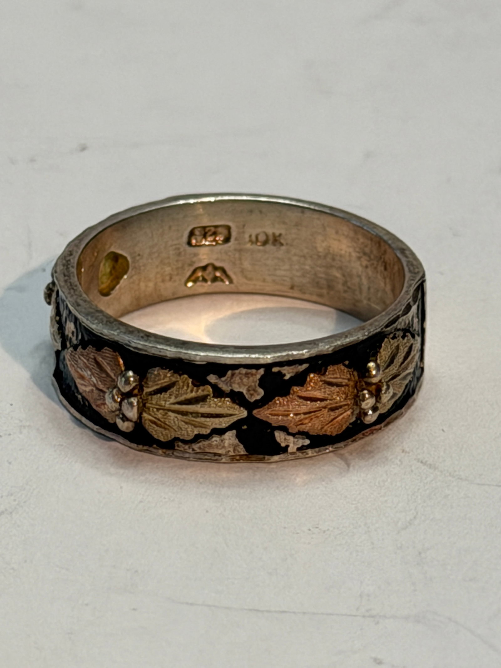 Black Hills Gold Sterling Silver Band Ring ? 10K Gold Leaf Accents ? Size 8: Black Hills Gold style band ring crafted in sterling silver with classic rose and yellow 10K gold leaf accents. Features the traditional grapevine leaf motif on an oxidized black enamel-style backgrou